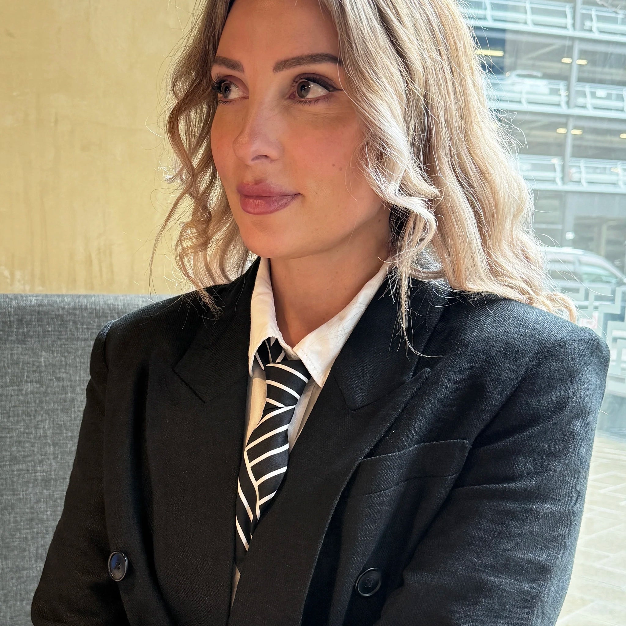 Woman wearing a suit with a striped tie indoors