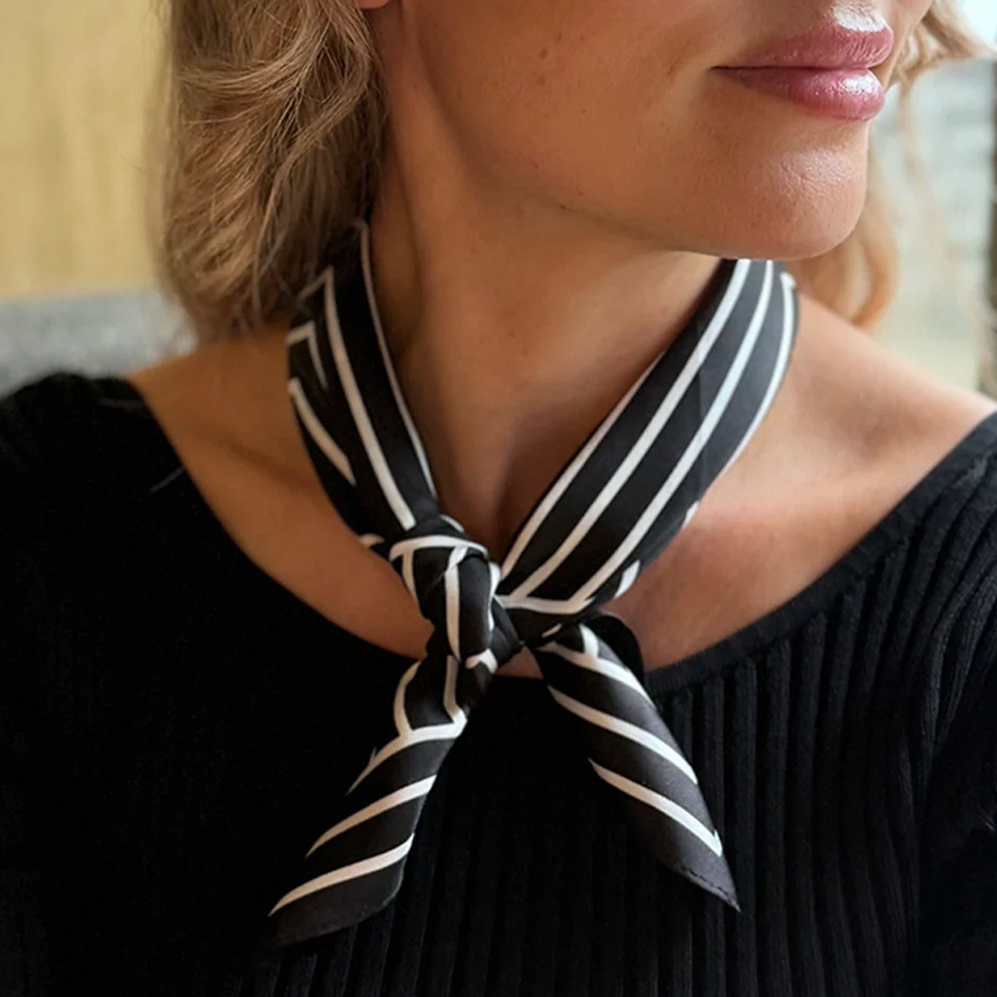 Woman wearing a black and white striped scarf around her neck.