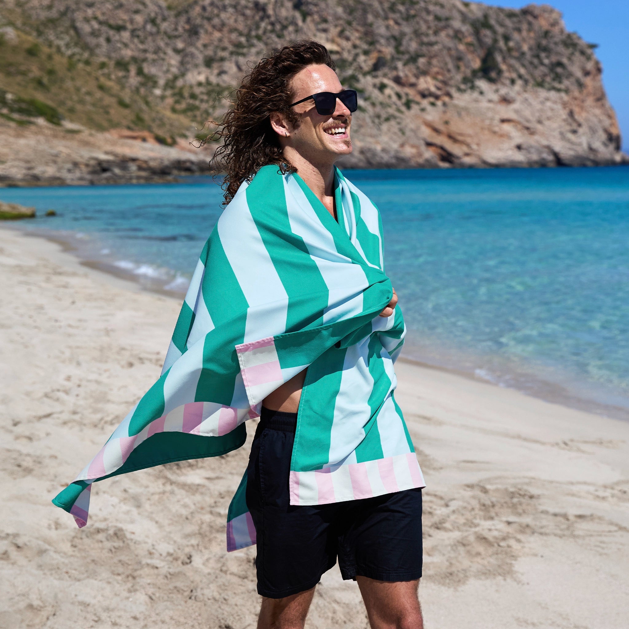 Person on a beach wearing a green and white striped towel