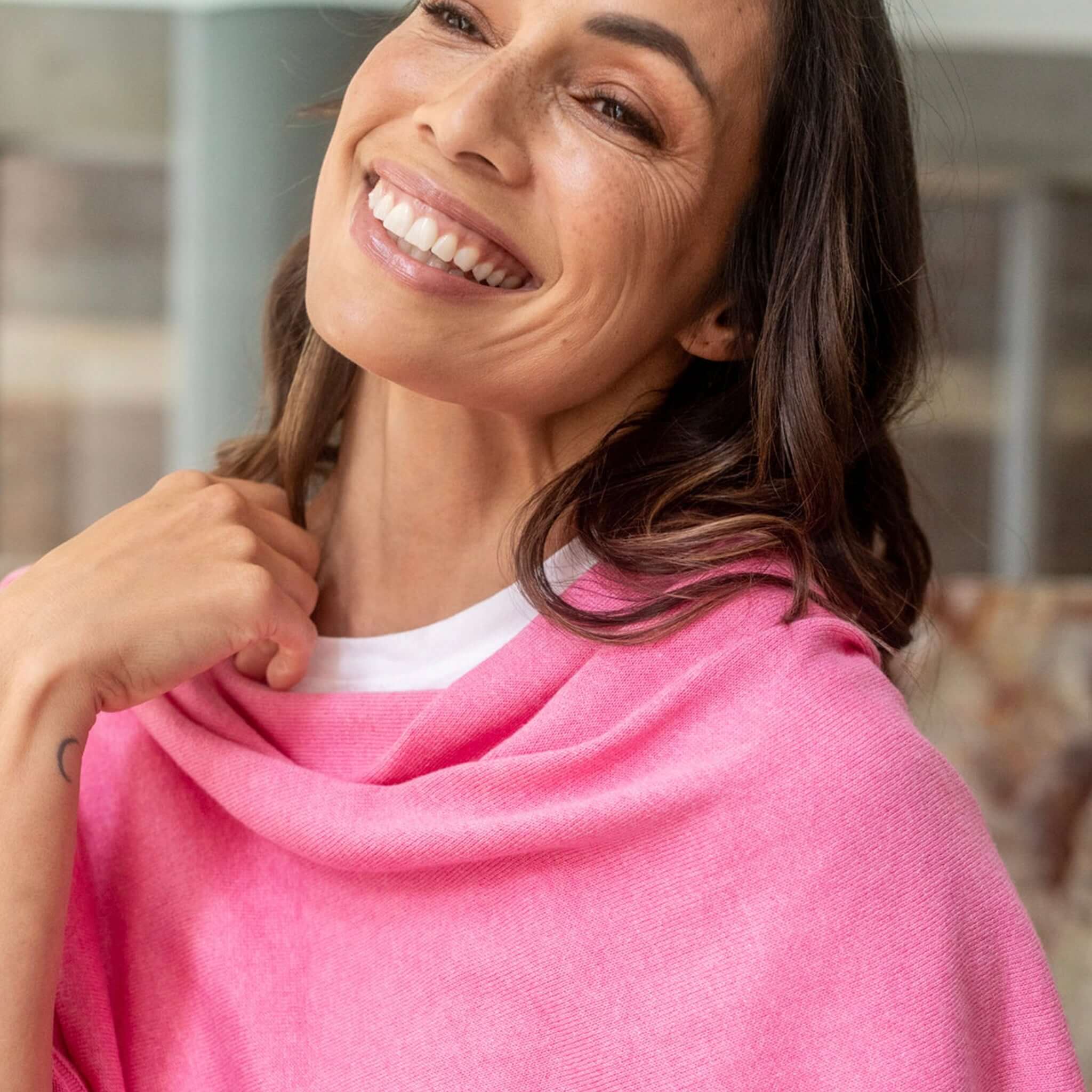 Woman smiling while wearing Esperance & Co Classic Cashmere Topper - Glam Pink, showcasing its elegance and versatility.
