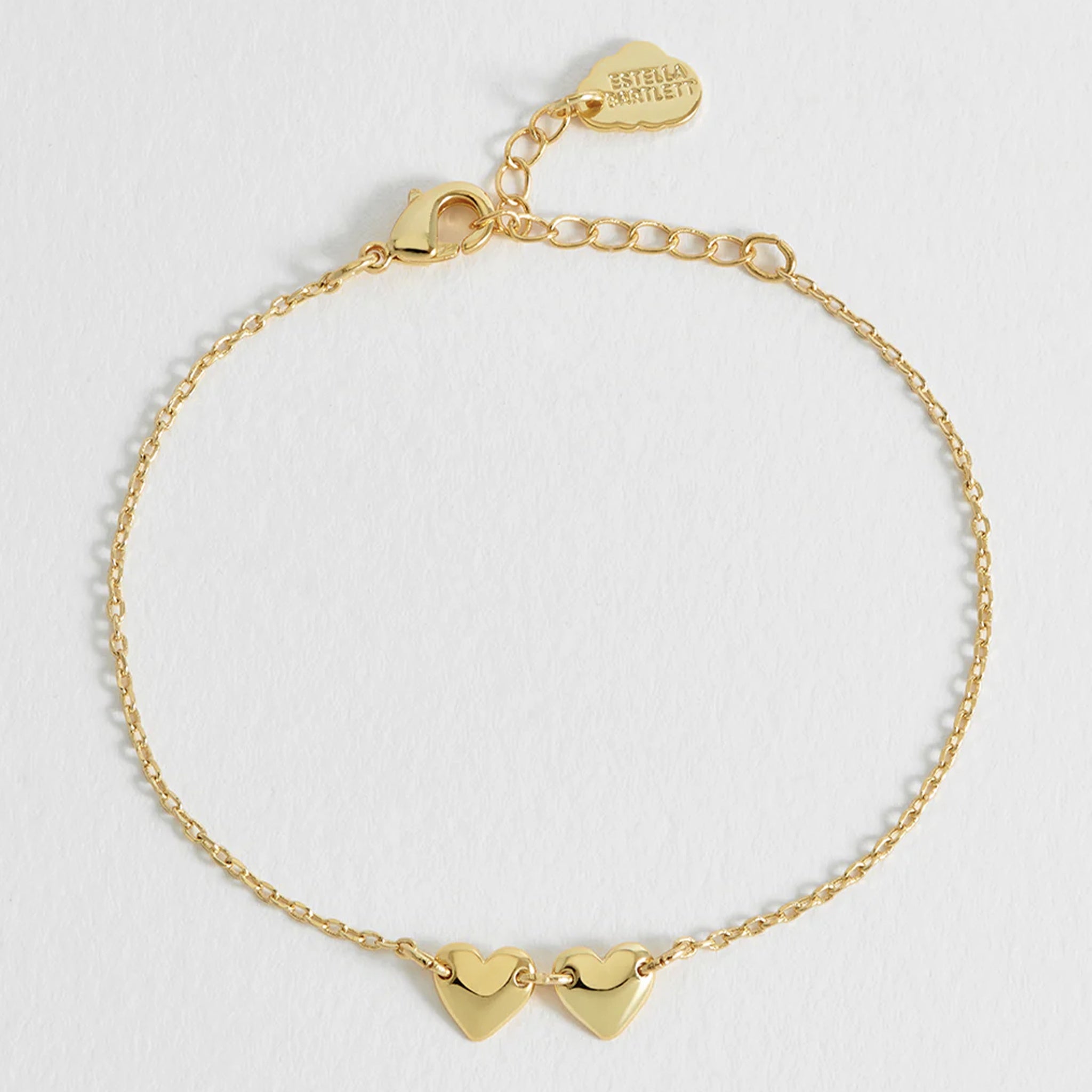 Gold bracelet with heart-shaped charms on a light gray background