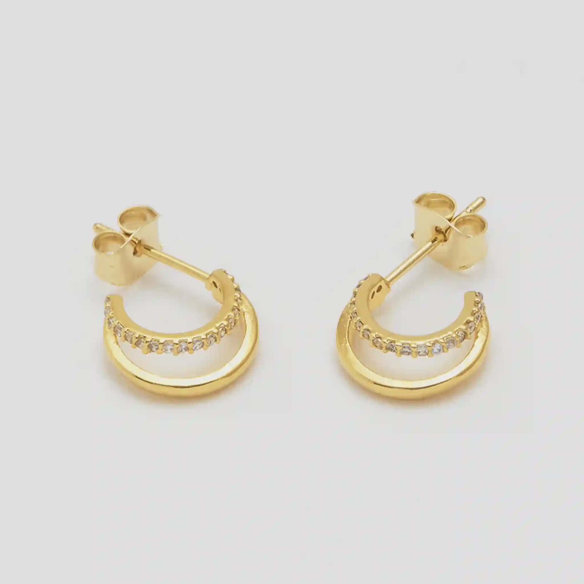 Gold hoop earrings with small diamonds on a light gray background