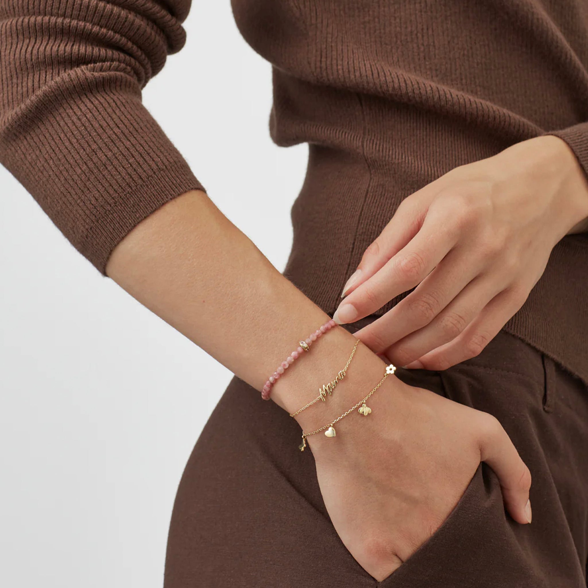 Close-up of a person wearing multiple gold bracelets on a plain background