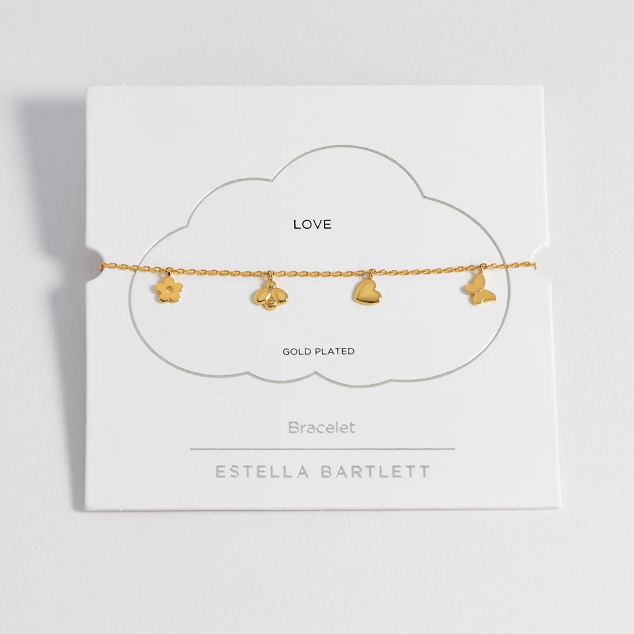 Gold-plated bracelet with heart charms on a white card with 'Estella Bartlett' branding.