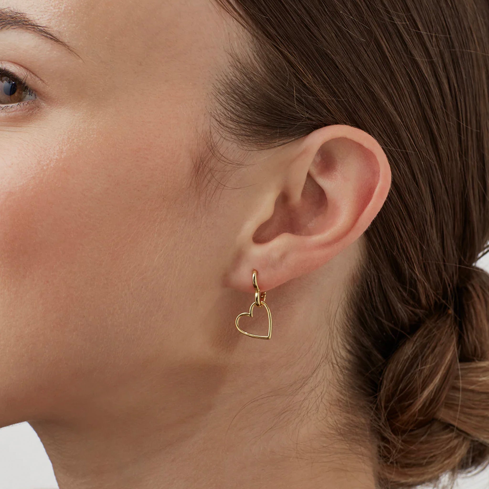 Close-up of a woman wearing a gold heart-shaped earring.