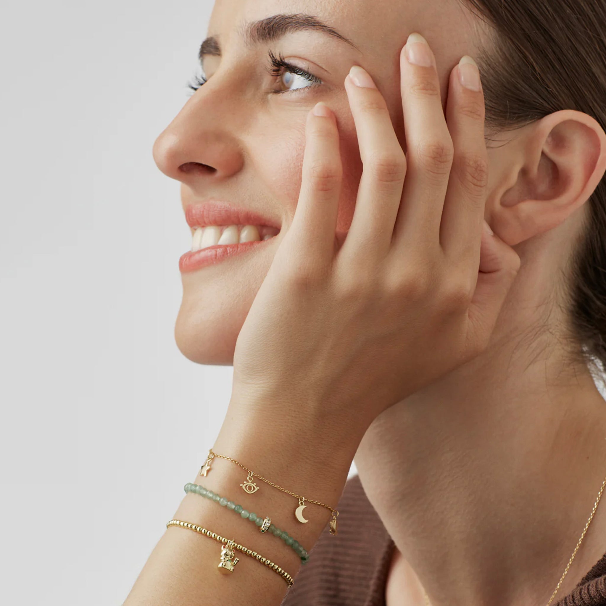 Woman wearing multiple gold bracelets on a light background