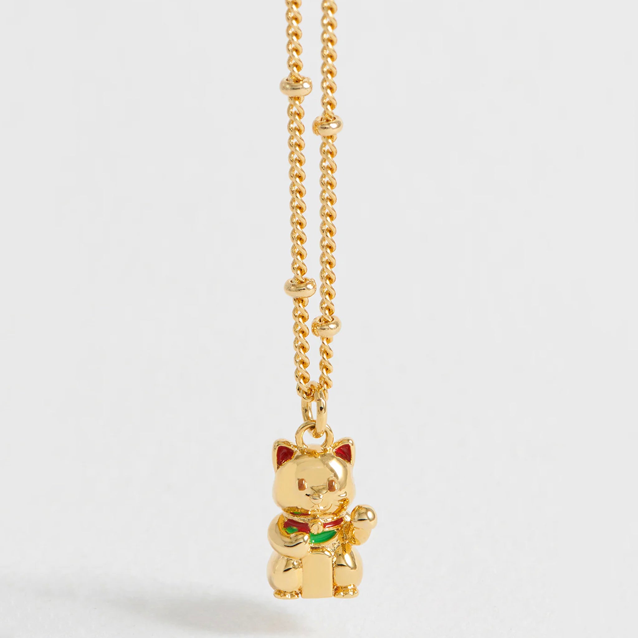 Gold cat-shaped pendant on a chain against a white background