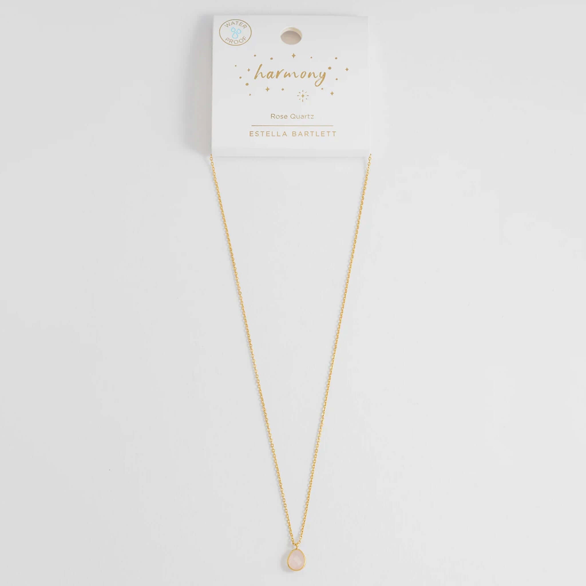Estella Bartlett Wellness Faceted Teardrop Necklace - Rose Quartz displayed on a card with gold chain and rose quartz pendant.