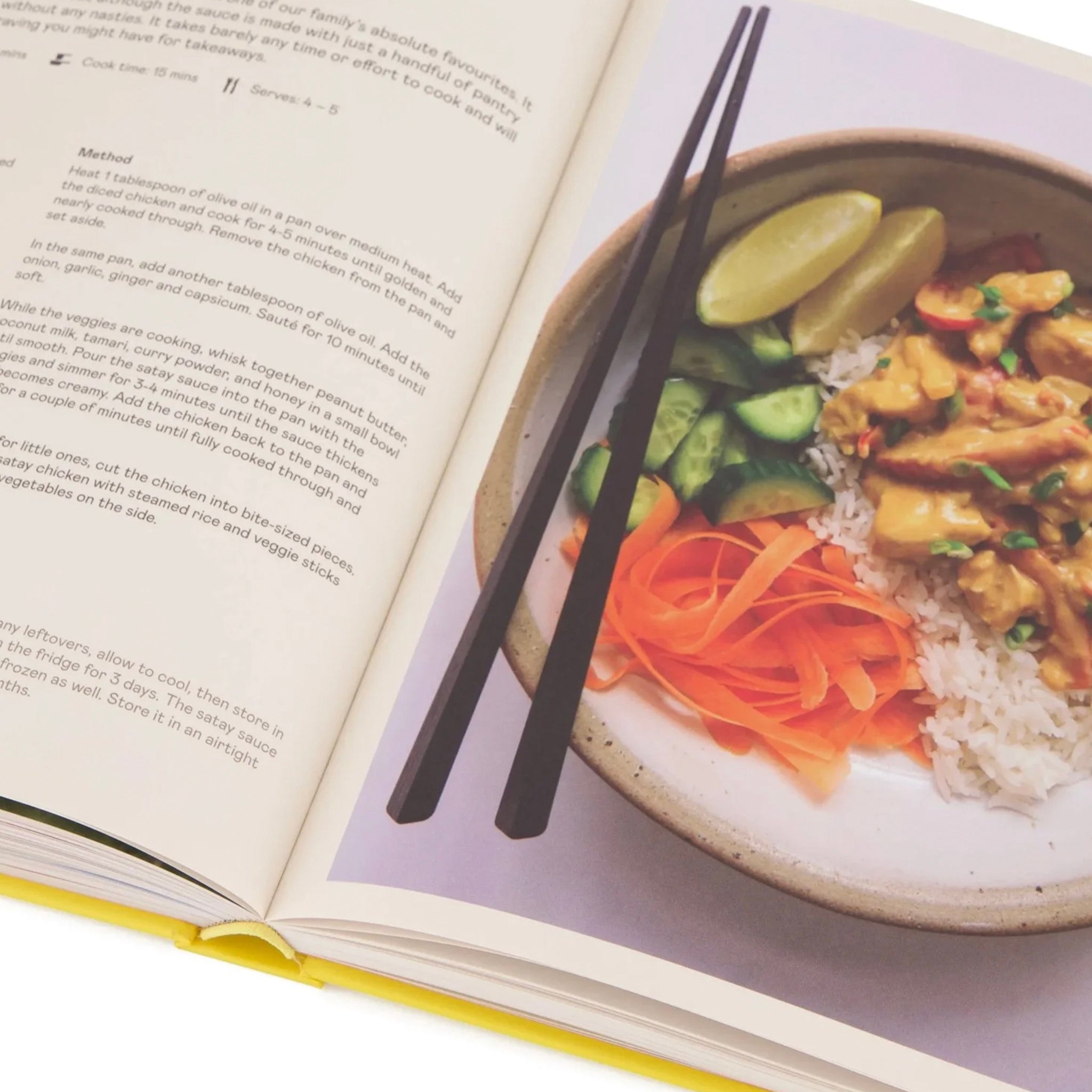 Open cookbook with a photograph of a bowl of food and chopsticks on a white background