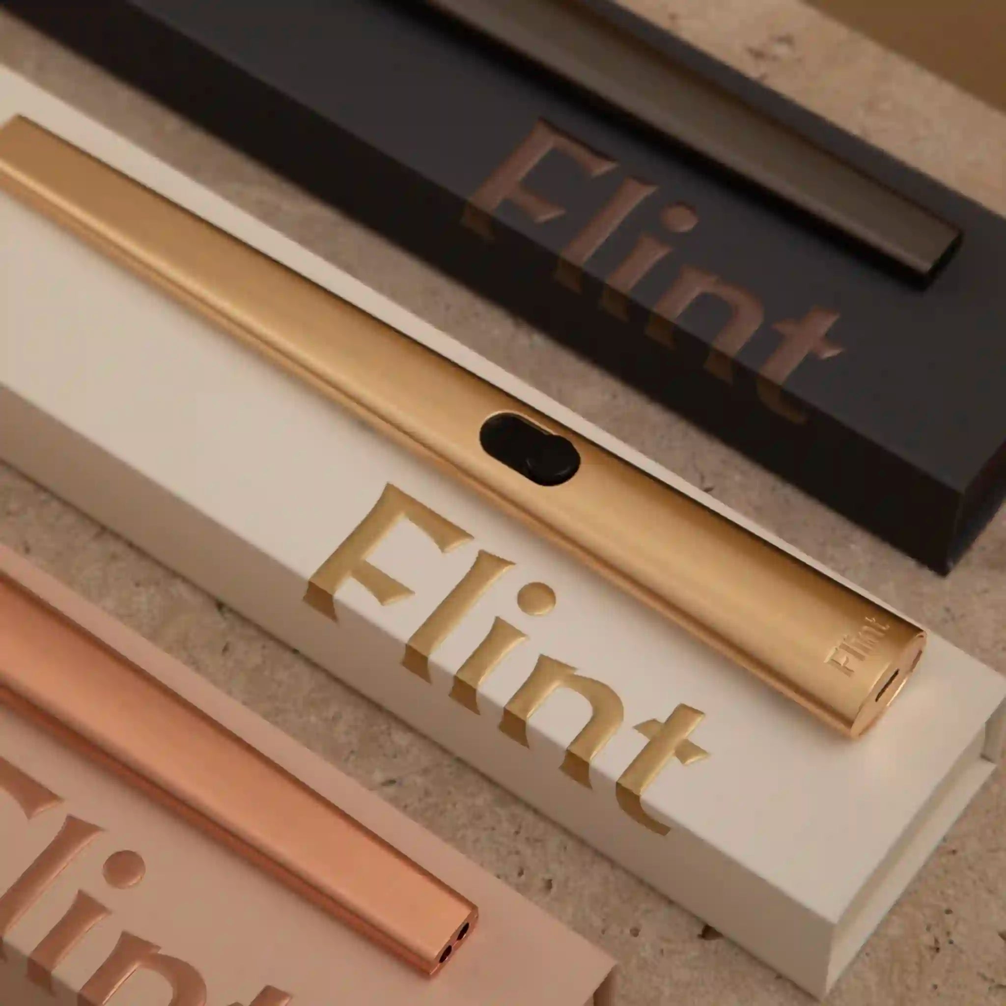 Gold and rose gold lighter with 'Flint' branding on a textured surface