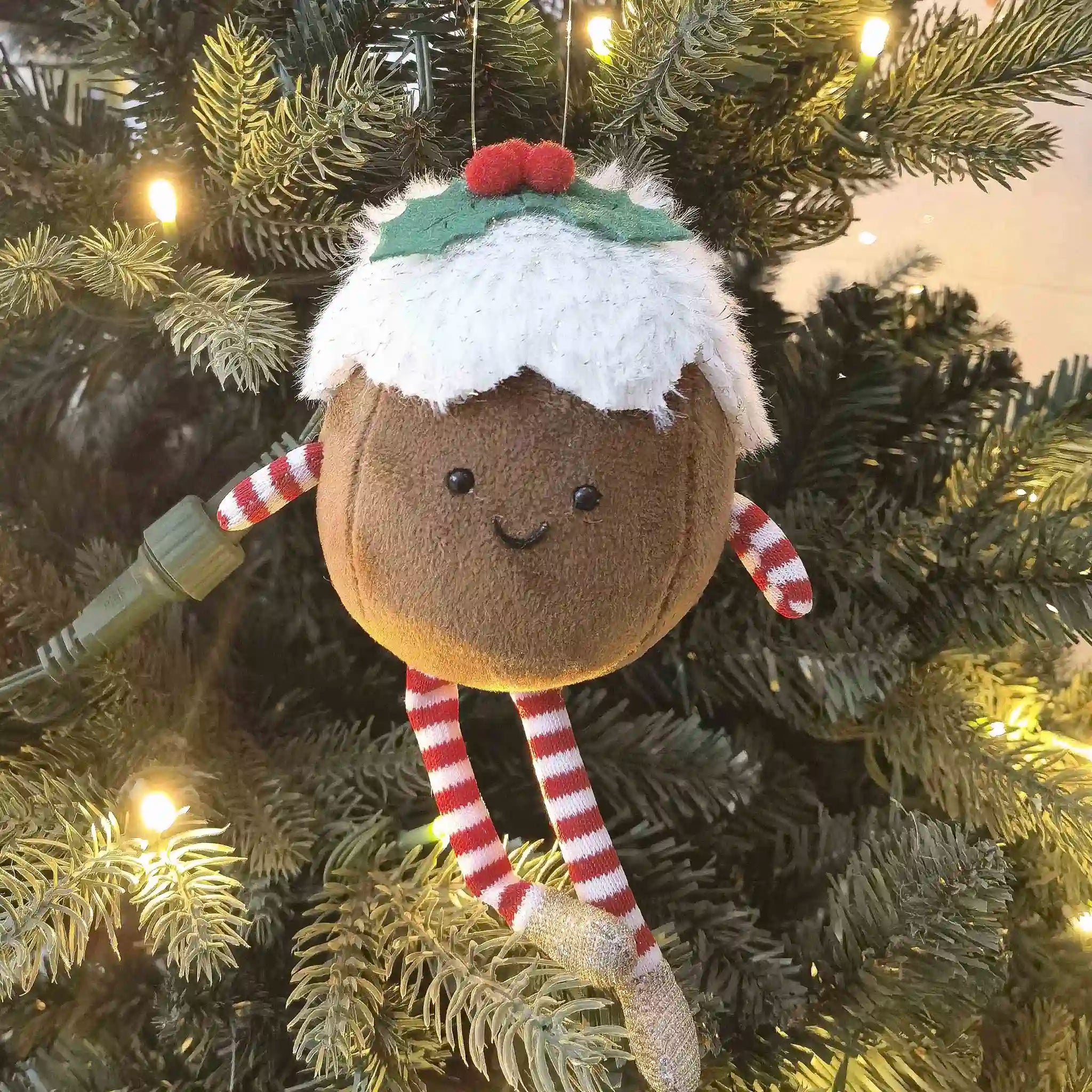 Decorative Christmas ornament shaped like a gingerbread man hanging on a tree.