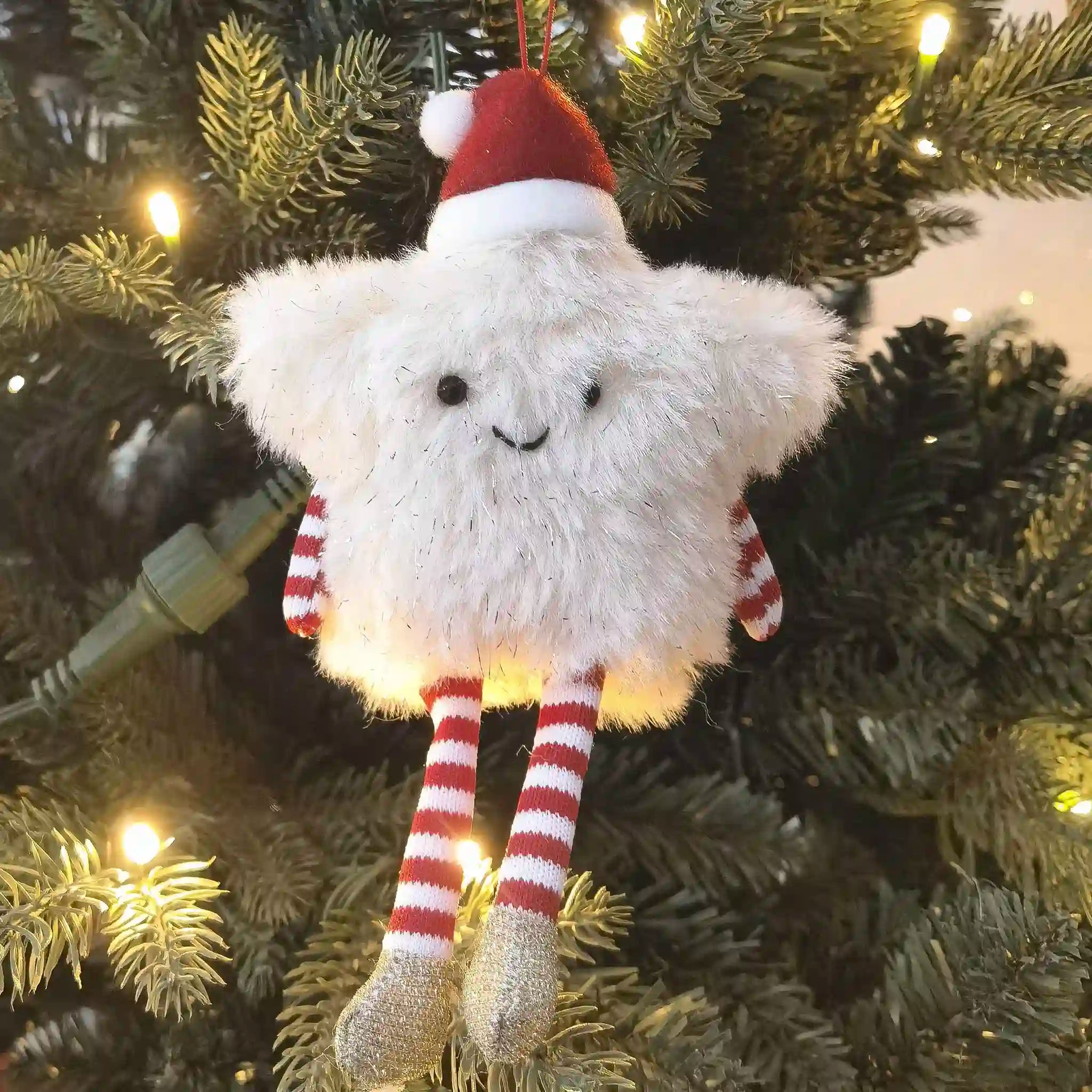 Plush toy cloud with a Santa hat hanging on a Christmas tree.