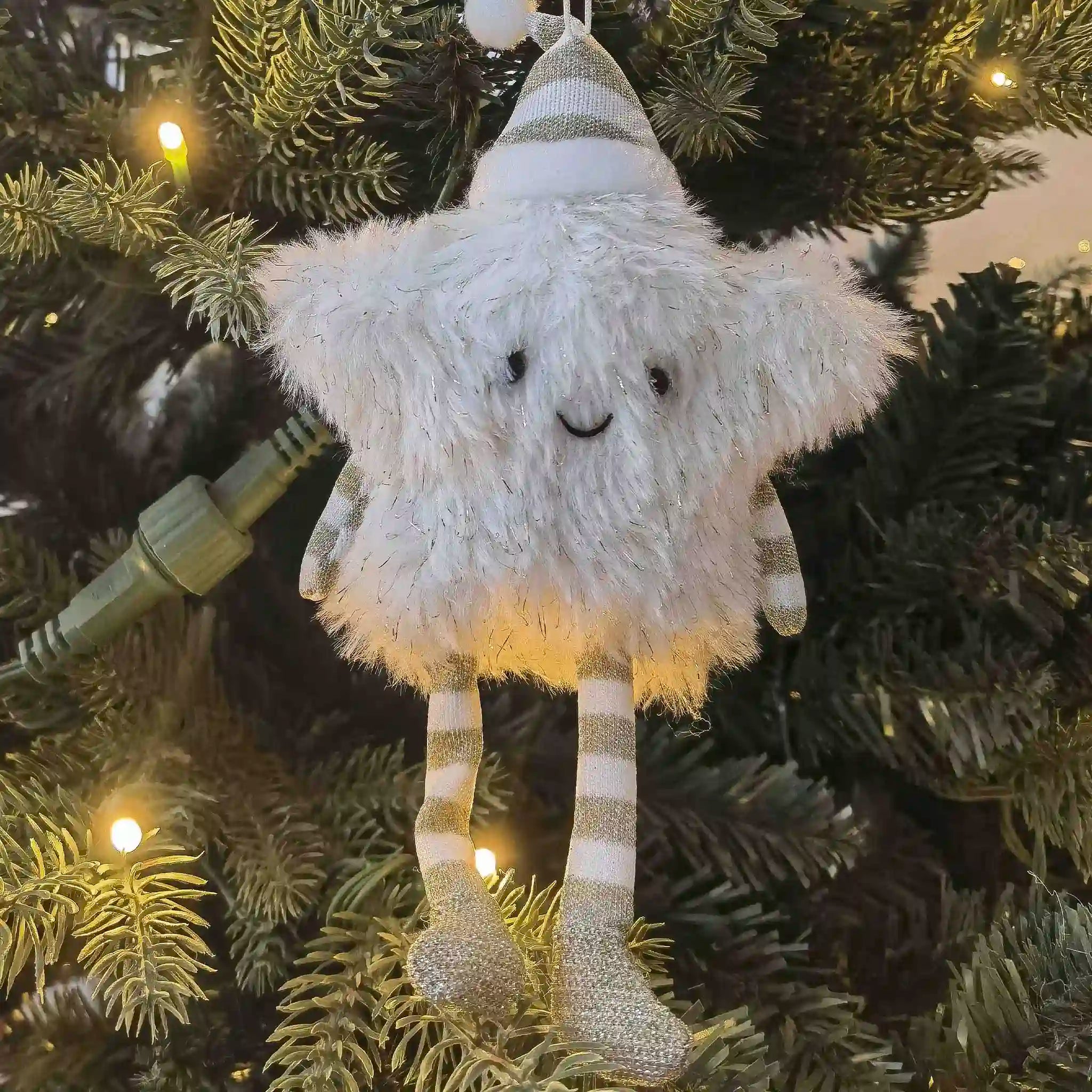 Plush gnome ornament hanging on a decorated Christmas tree.