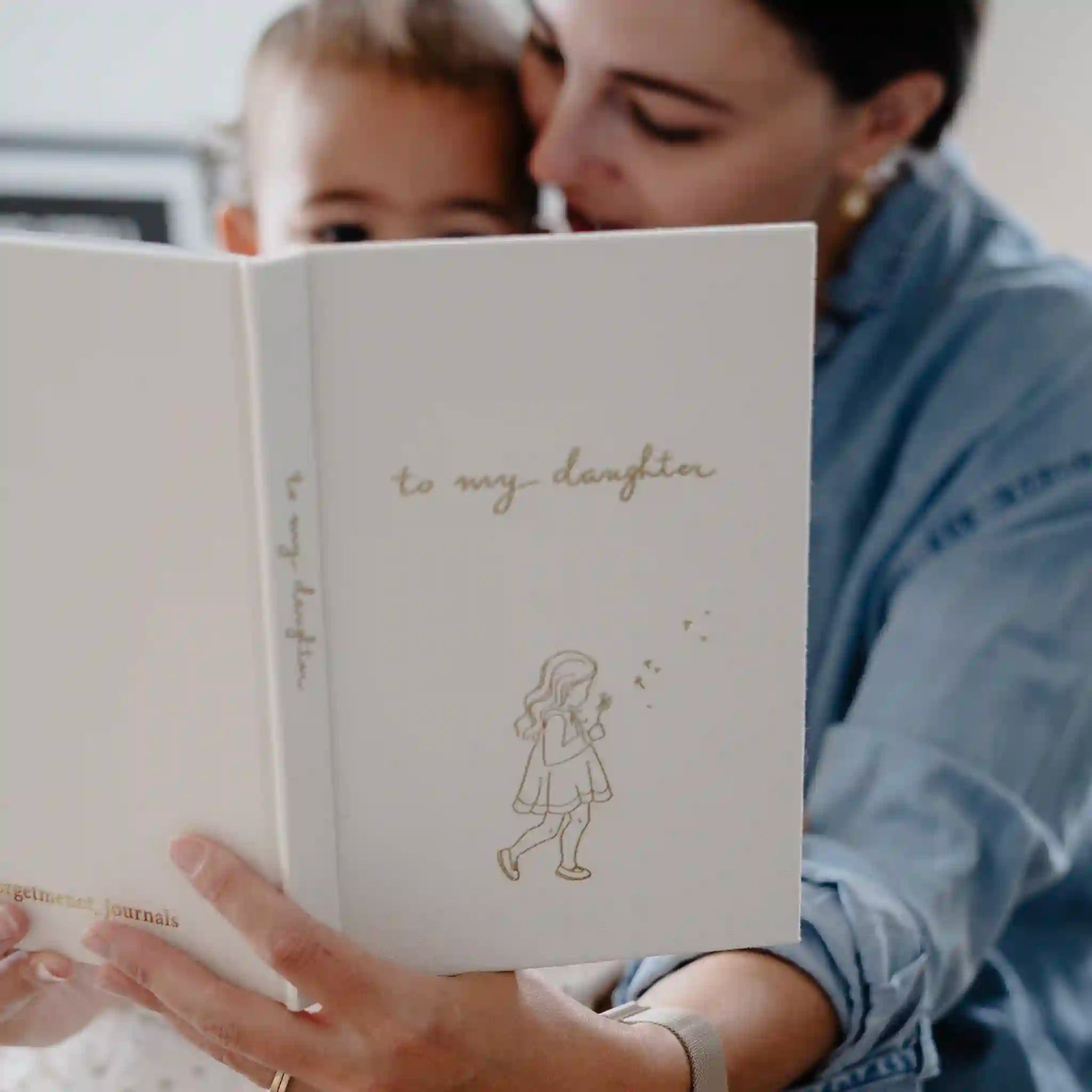 Woman and child reading a book together, with the title 'to my daughter' on the cover.