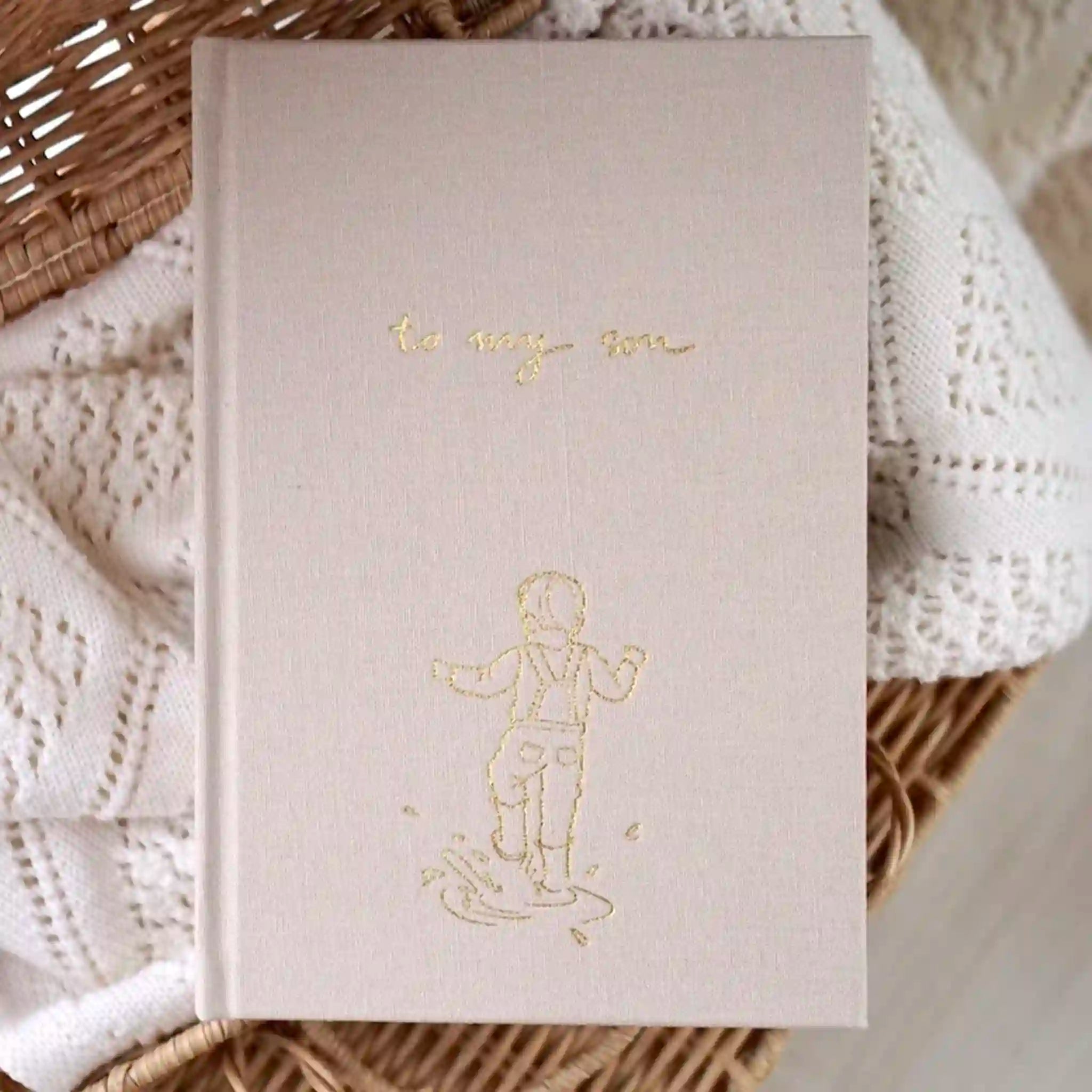 Beige journal with gold foil design and text on a textured surface