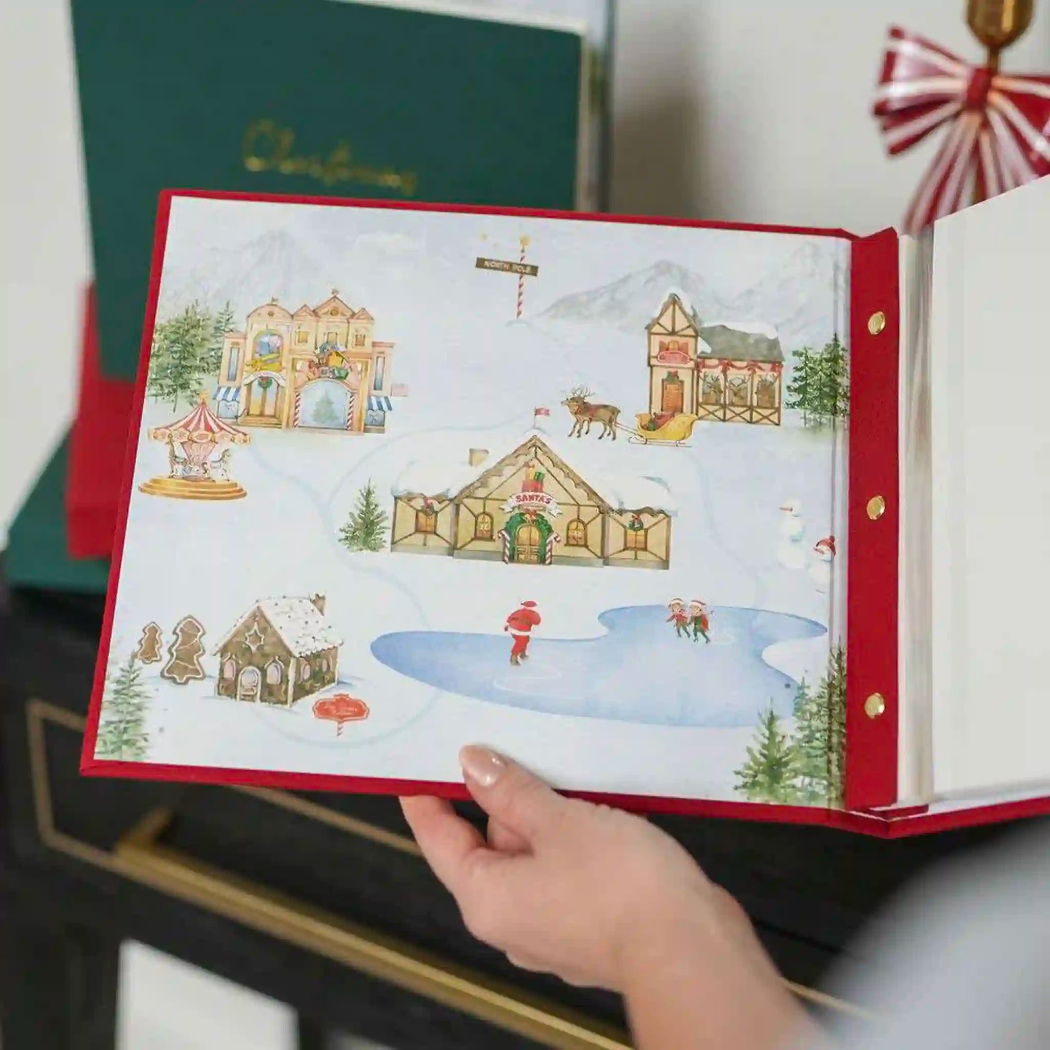 Hand holding a Christmas-themed book with illustrated winter scenes