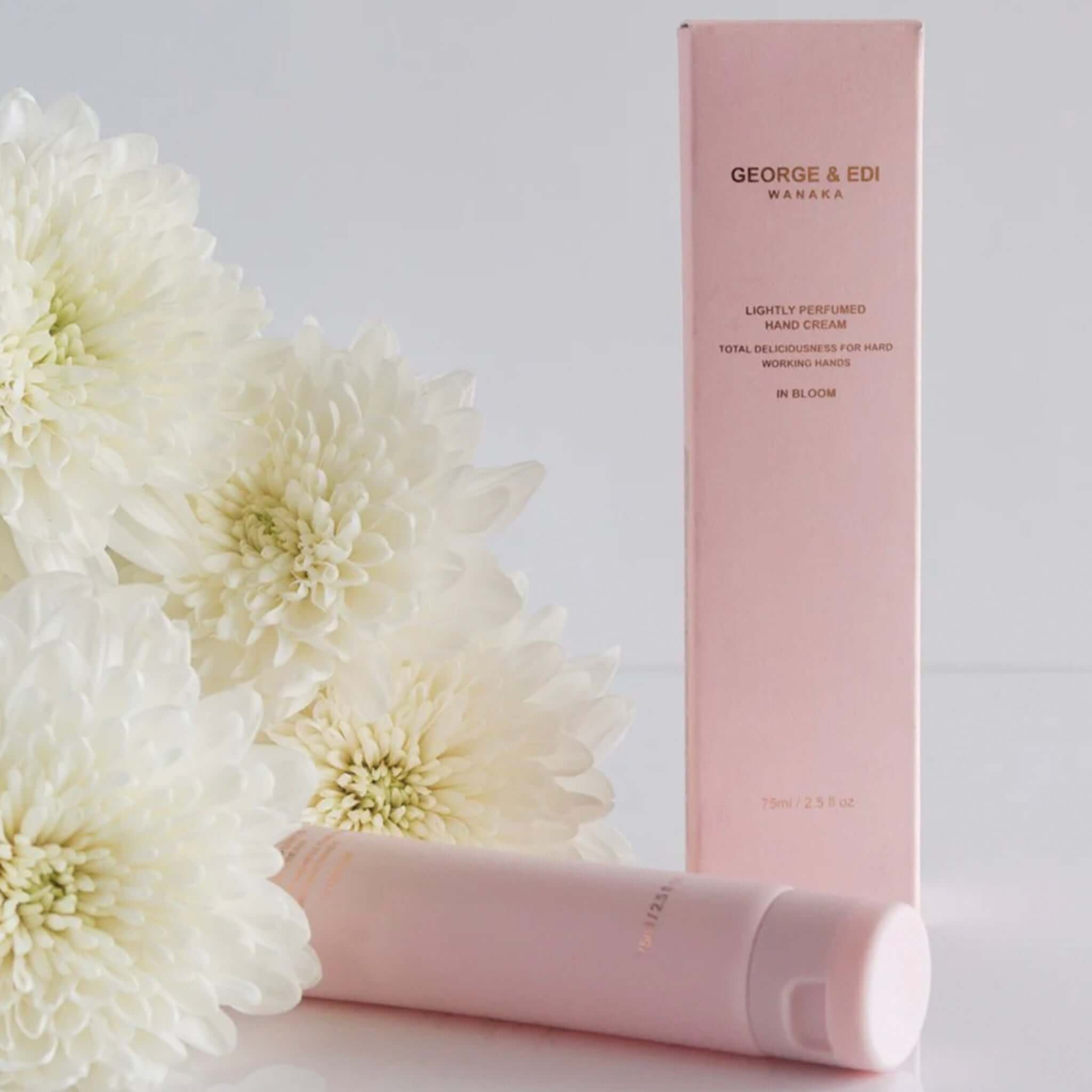 George & Edi Fragrance Hand Cream - In Bloom with floral background, showcasing packaging and hand cream tube.
