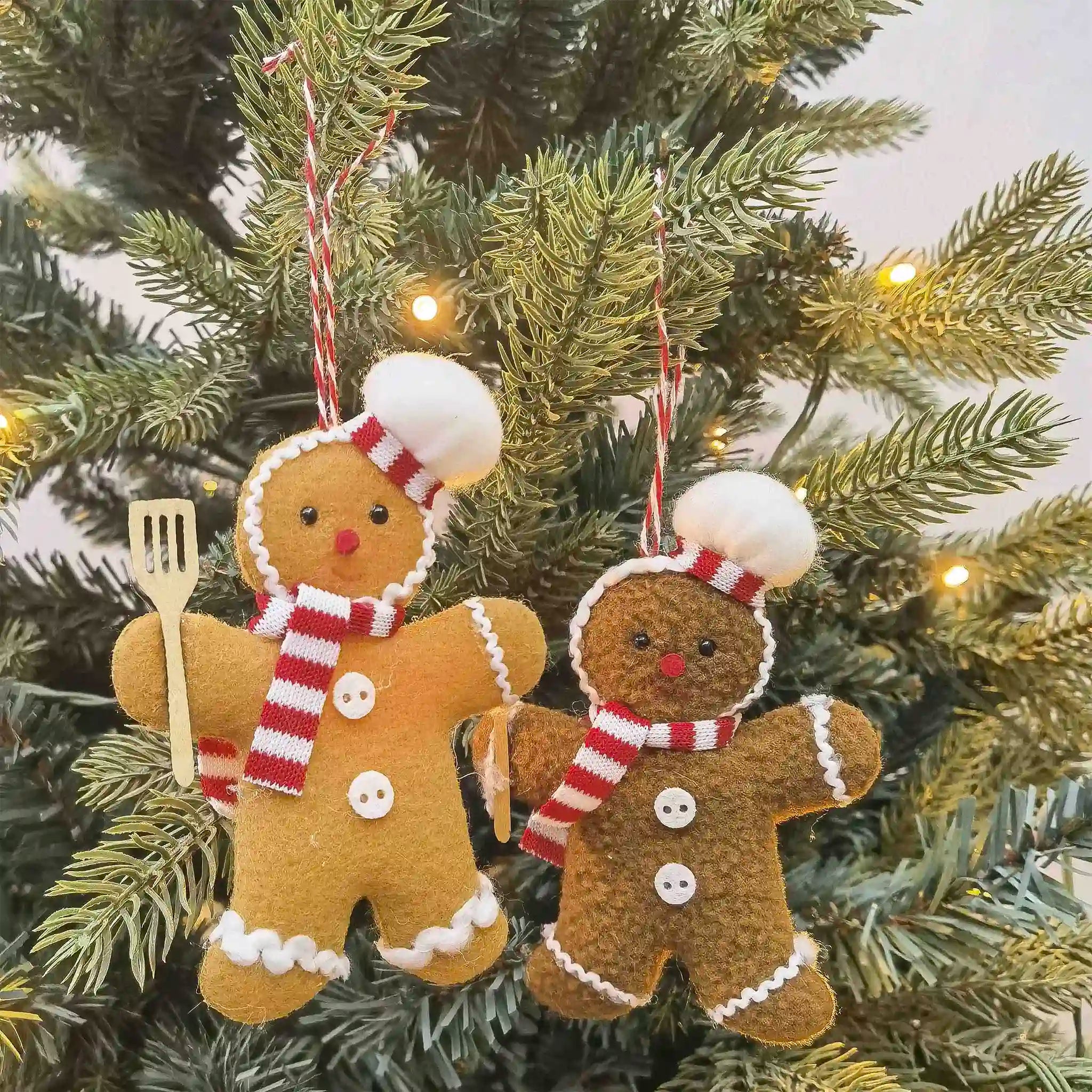 Two gingerbread man ornaments on a Christmas tree.