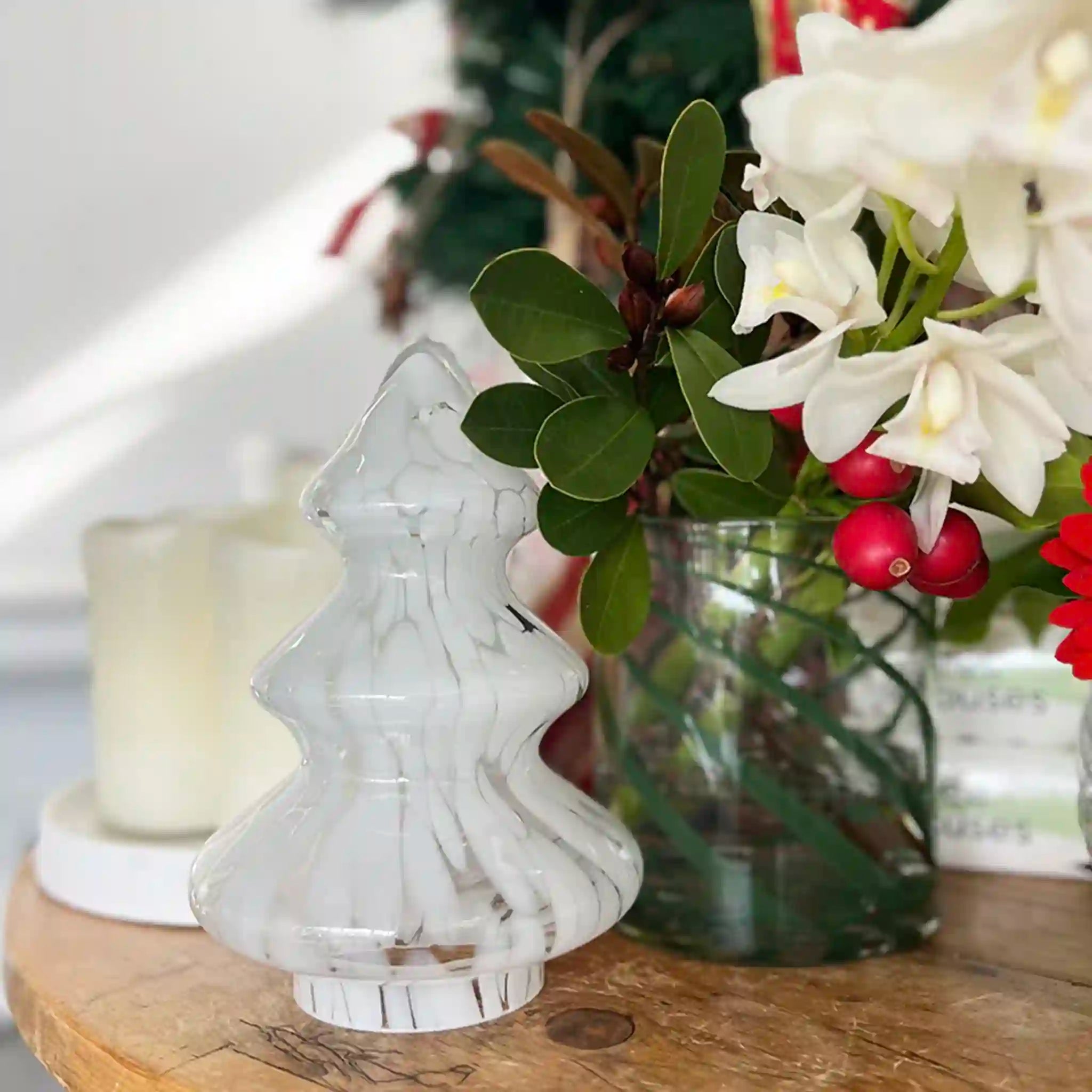 Decorative glass chess piece on a wooden surface with flowers and a candle in the background