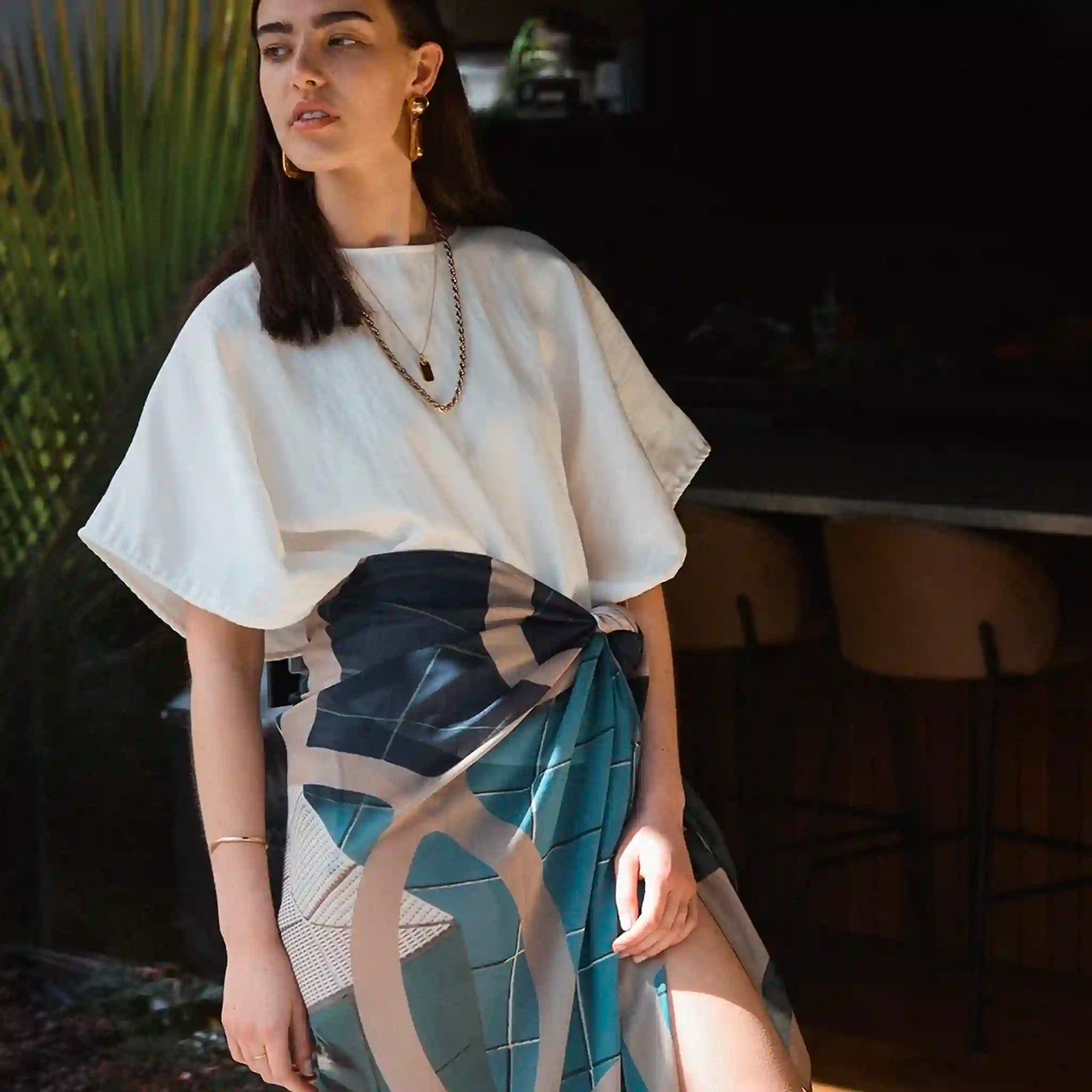 Woman wearing a white top and patterned skirt outdoors