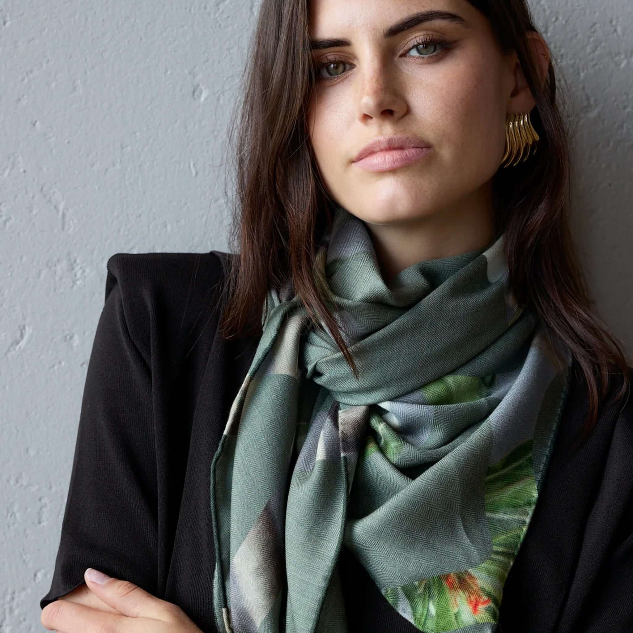 Alt Tag: Model wearing Good & Co Heritage Triangle Wool & Silk Scarf - Olive, oversized triangle scarf with double-sided print and contrast hem