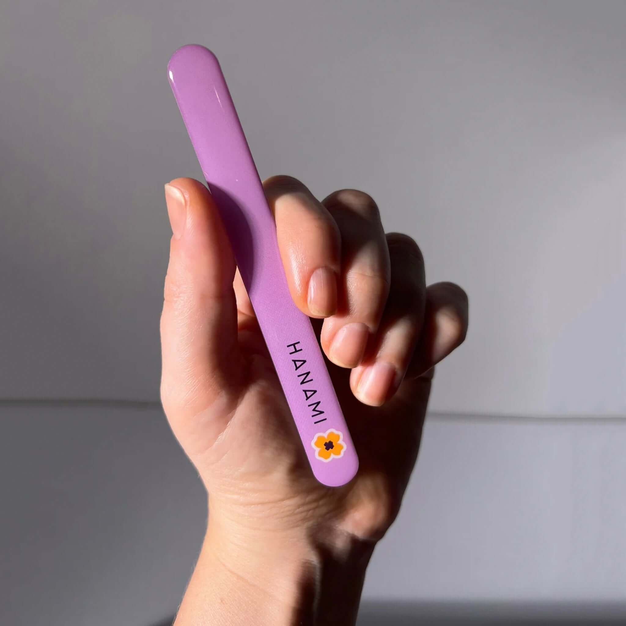 Alt Tag: Hanami Nano Glass Nail File & Buffer in hand, purple tempered glass nano nail file for shaping, buffing and polishing nails