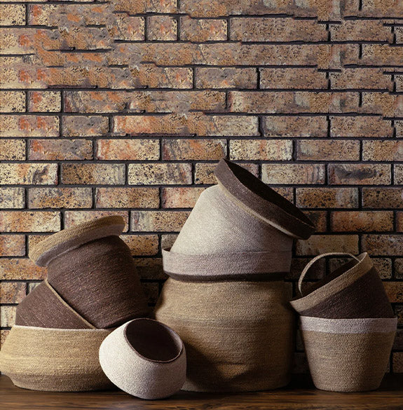 Set of woven baskets in various sizes against a brick wall.