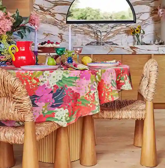 Colorful floral tablecloth on a dining table with chairs in a kitchen setting.
