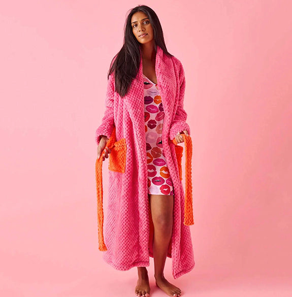 Woman wearing a pink robe with orange trim on a pink background