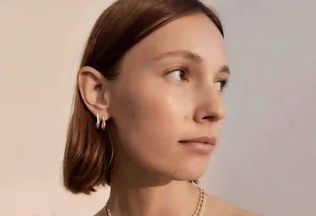 Close-up of a woman wearing earrings with a neutral background