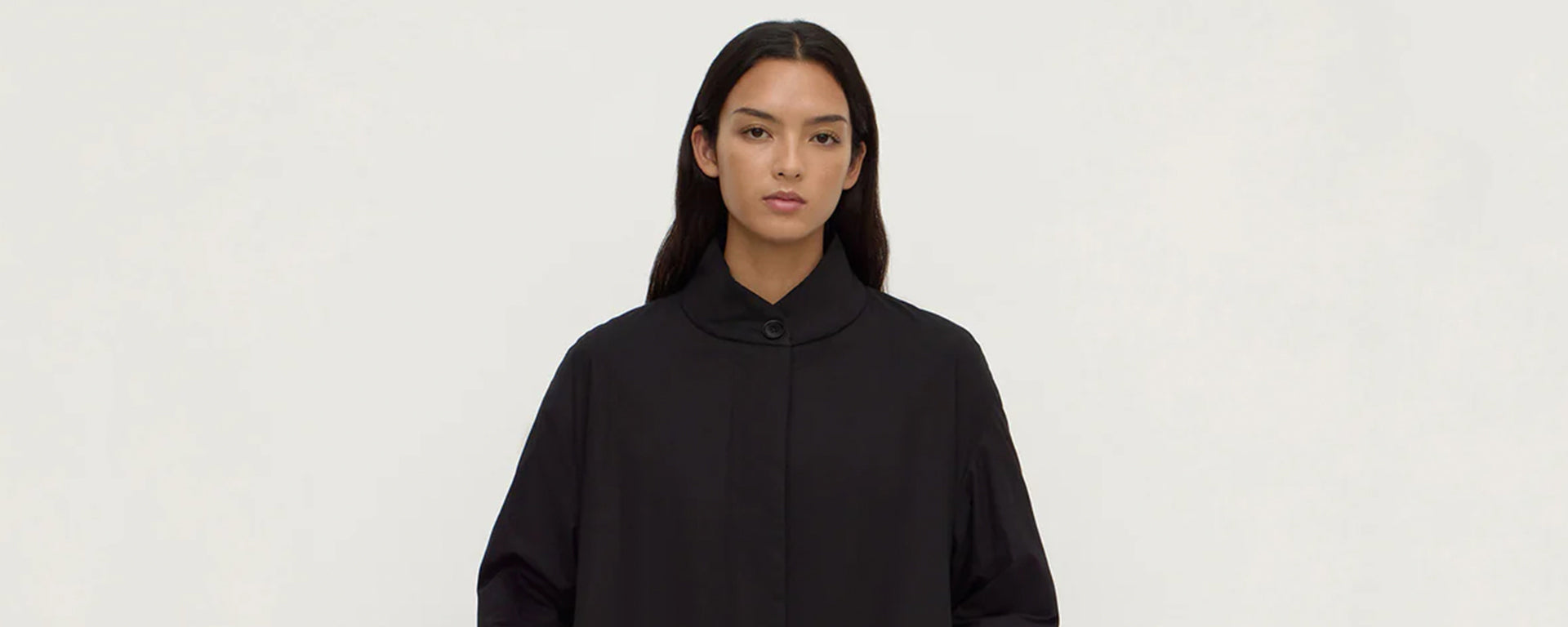 Person wearing a black coat against a white background