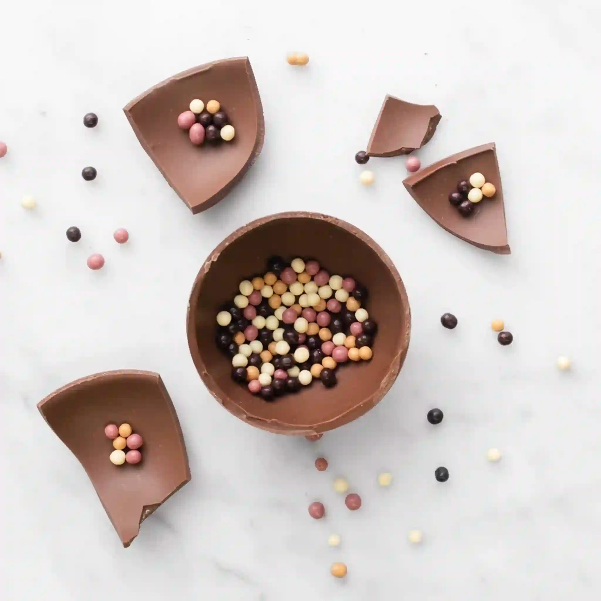 Chocolate bowls filled with colorful candies on a white background
