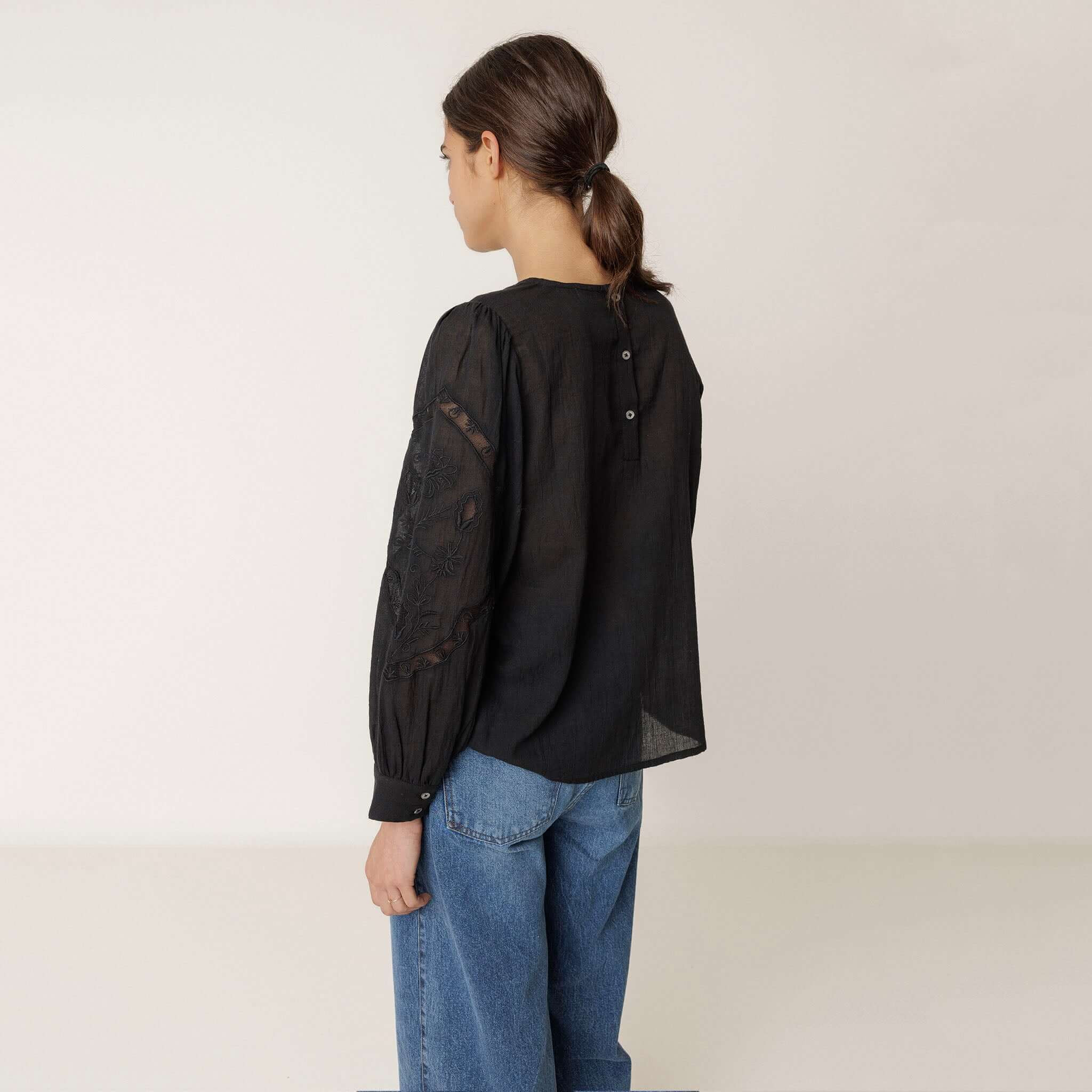 Alt Tag: Indi & Cold Organic Cotton Romantic Embroidered Blouse - Black back view, sheer embroidered sleeves, button detail, A-line silhouette