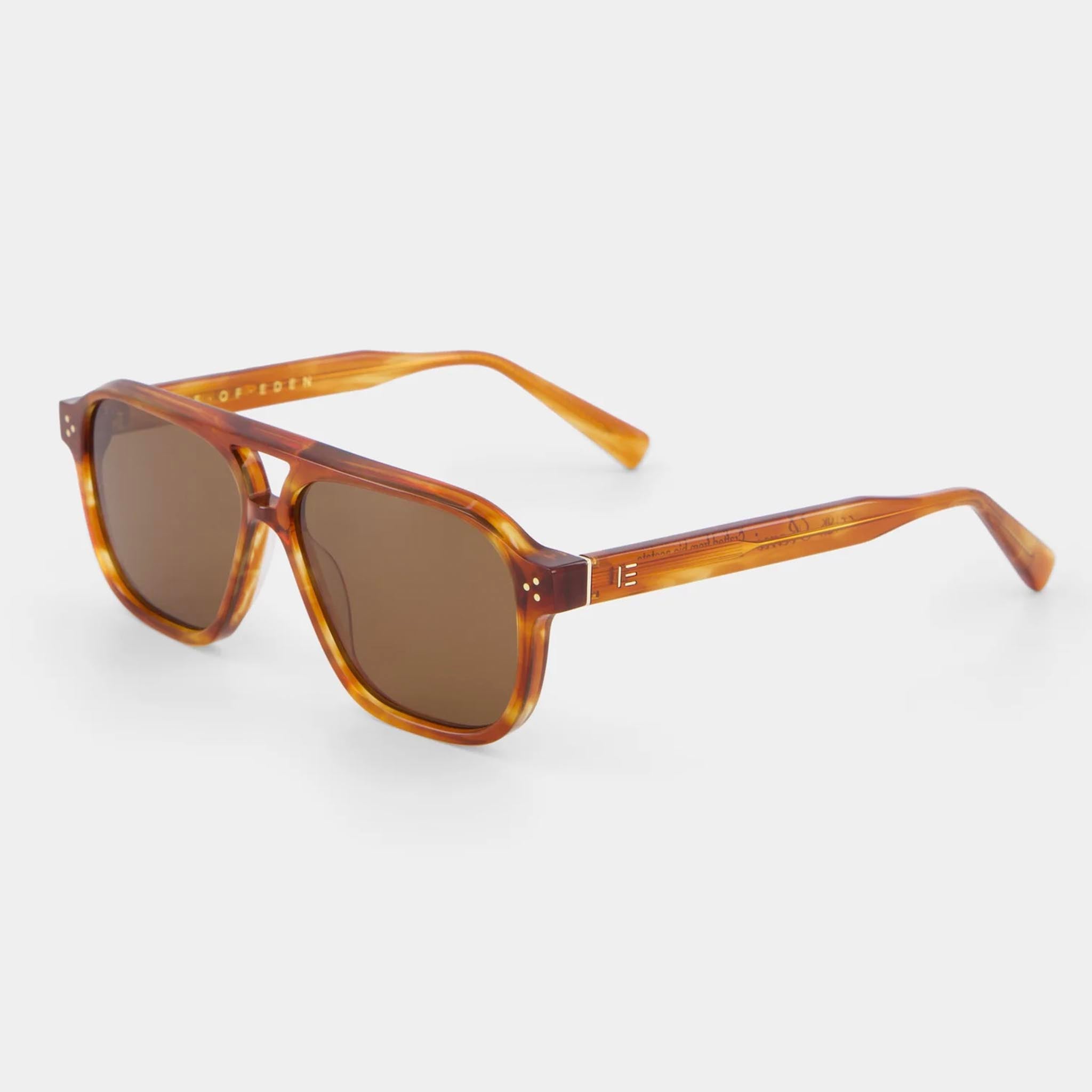 Sunglasses with tortoiseshell frame and brown lenses on a light gray background