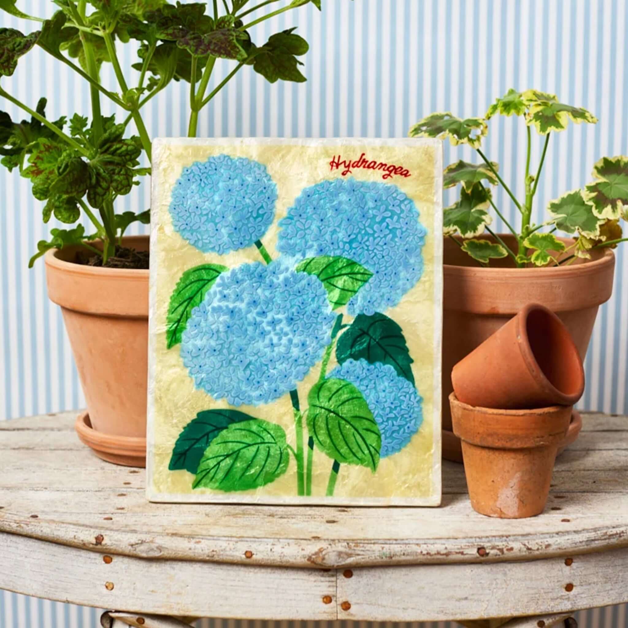 Jones & Co Capiz Shell Market Wall Art - Hydrangea featuring blue hydrangeas against a warm golden background.