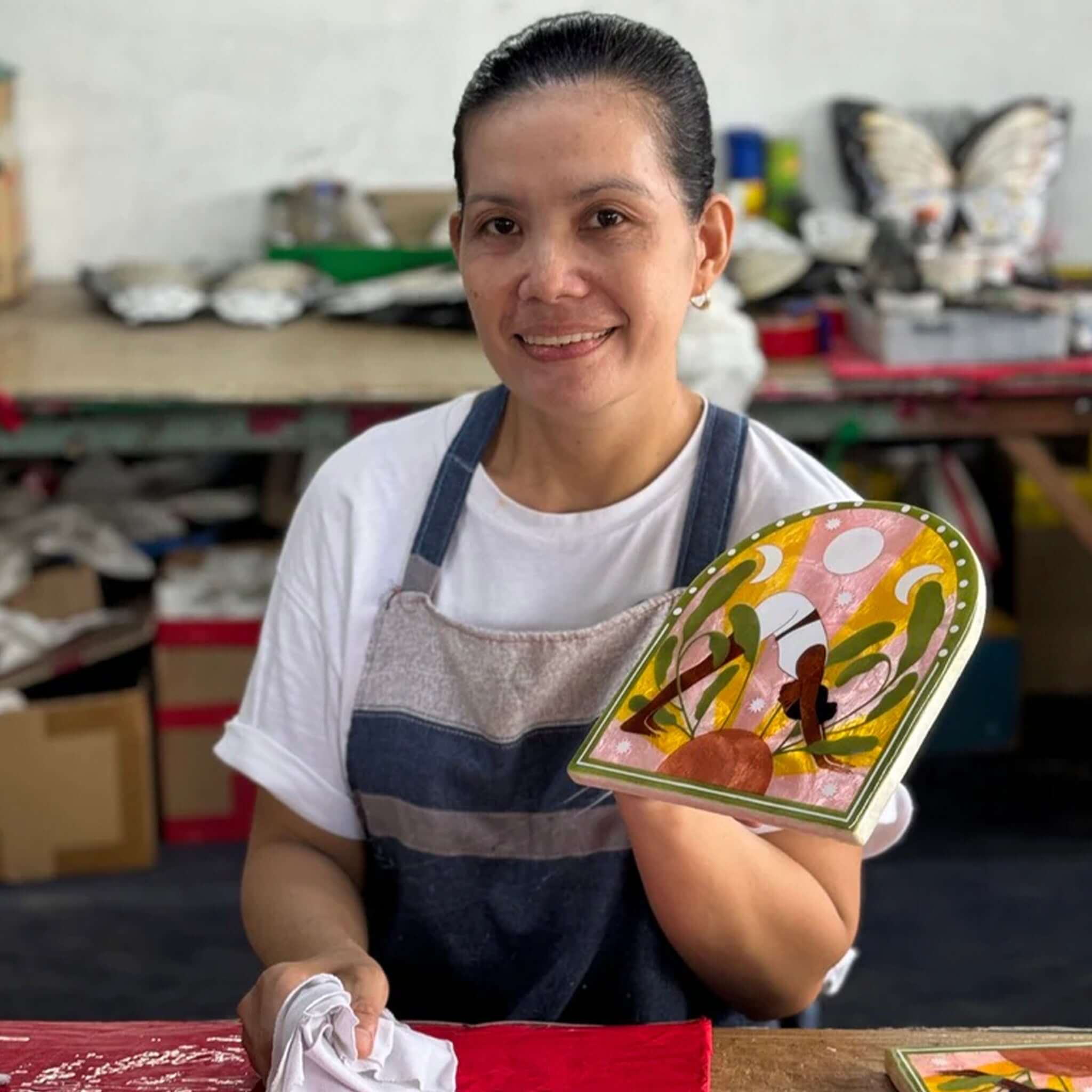 Artisan showcasing the Jones & Co Capiz Shell Market Wall Art - Pansy in a creative workshop setting.