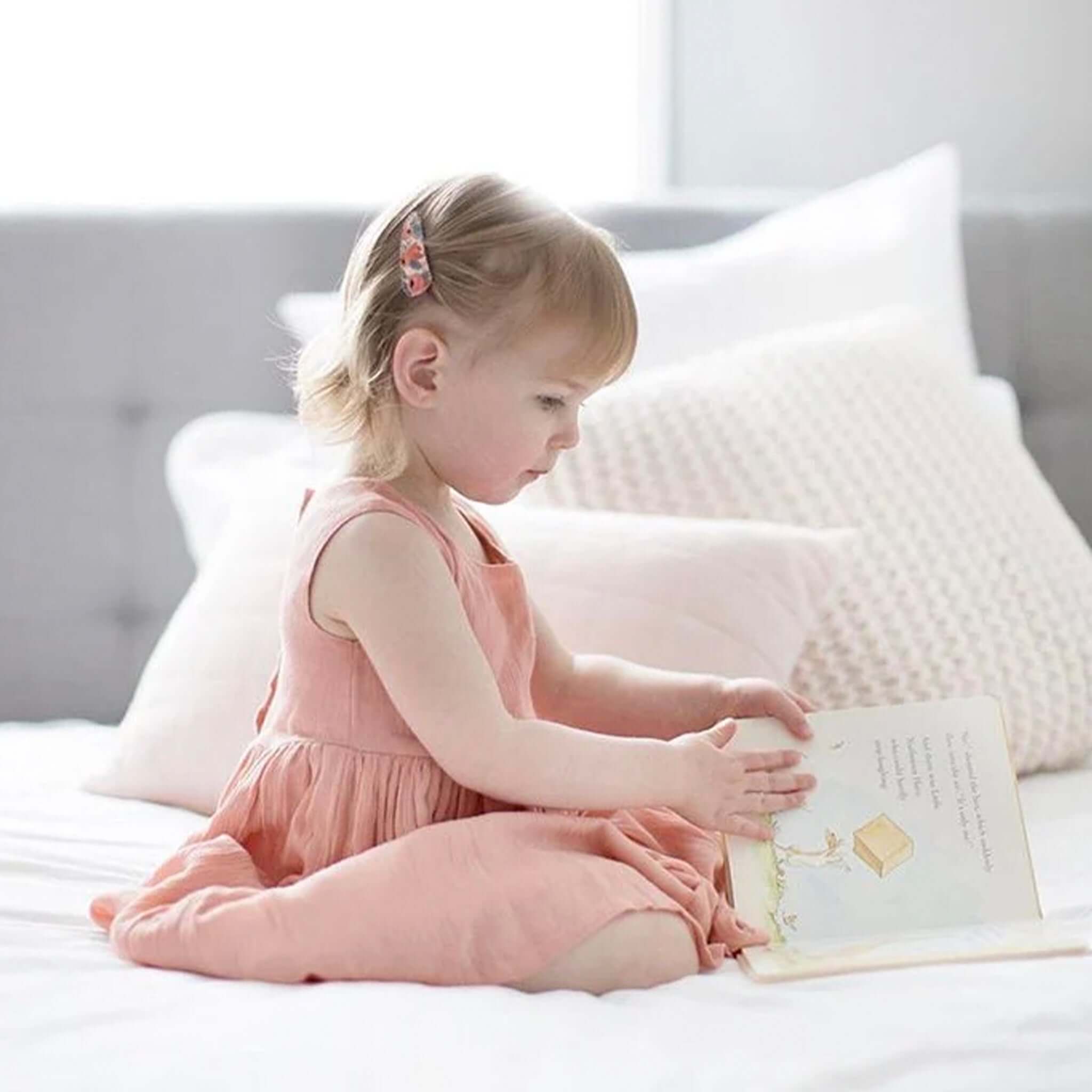 Alt Tag: Josie Joan's Hair Clip Set - Anna fabric-covered scalloped snap clips in Liberty London print worn by child reading on bed