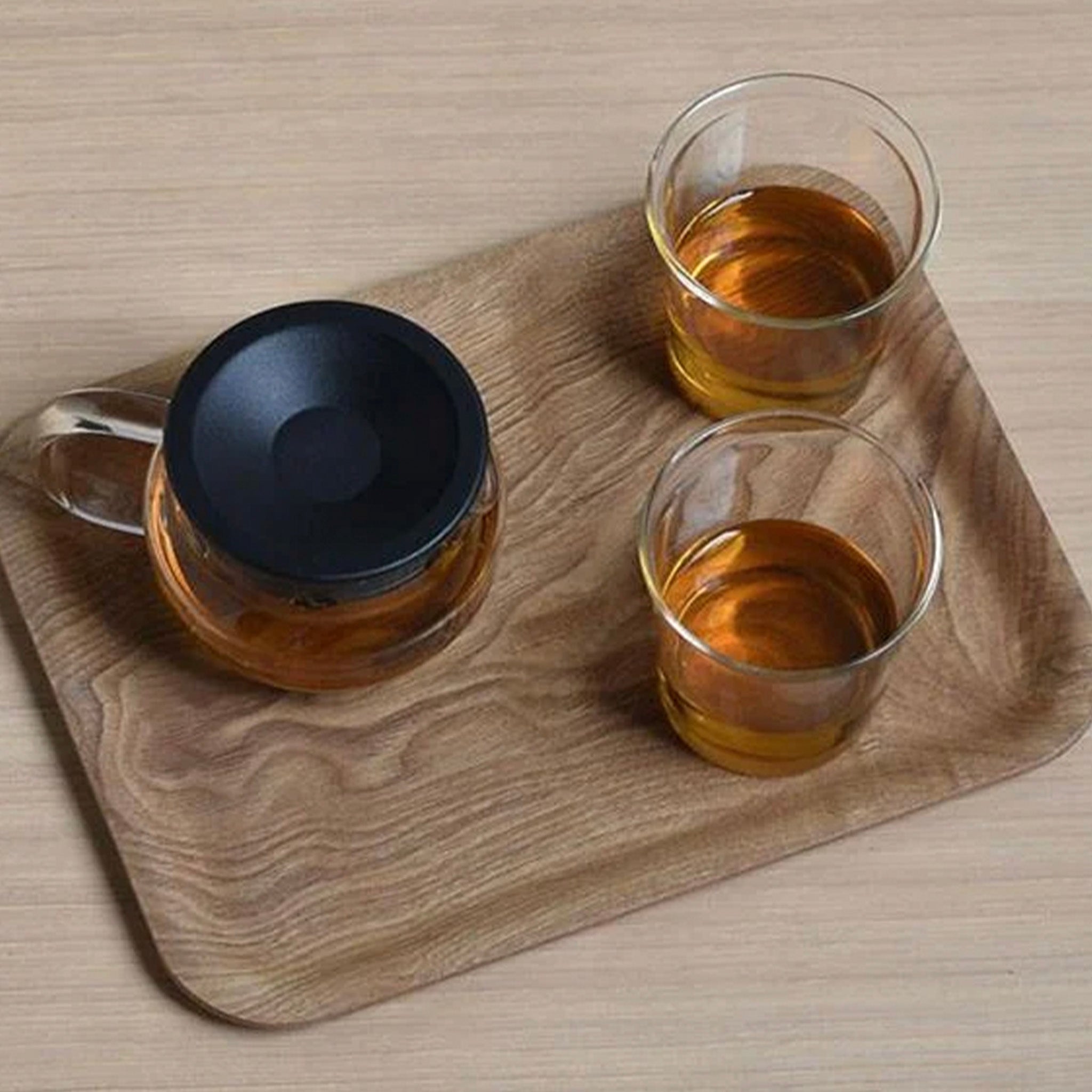 Two glass cups with tea on a wooden tray