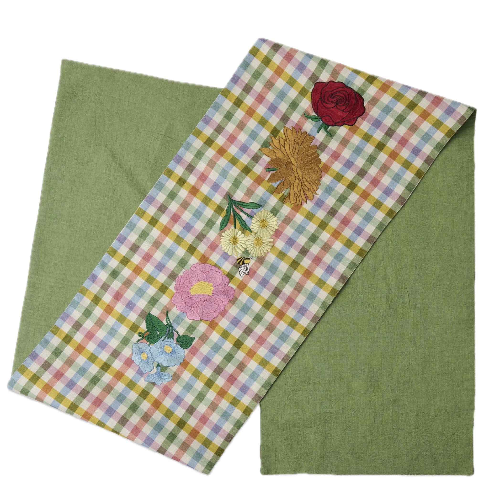 Floral embroidered table runner on a green fabric background