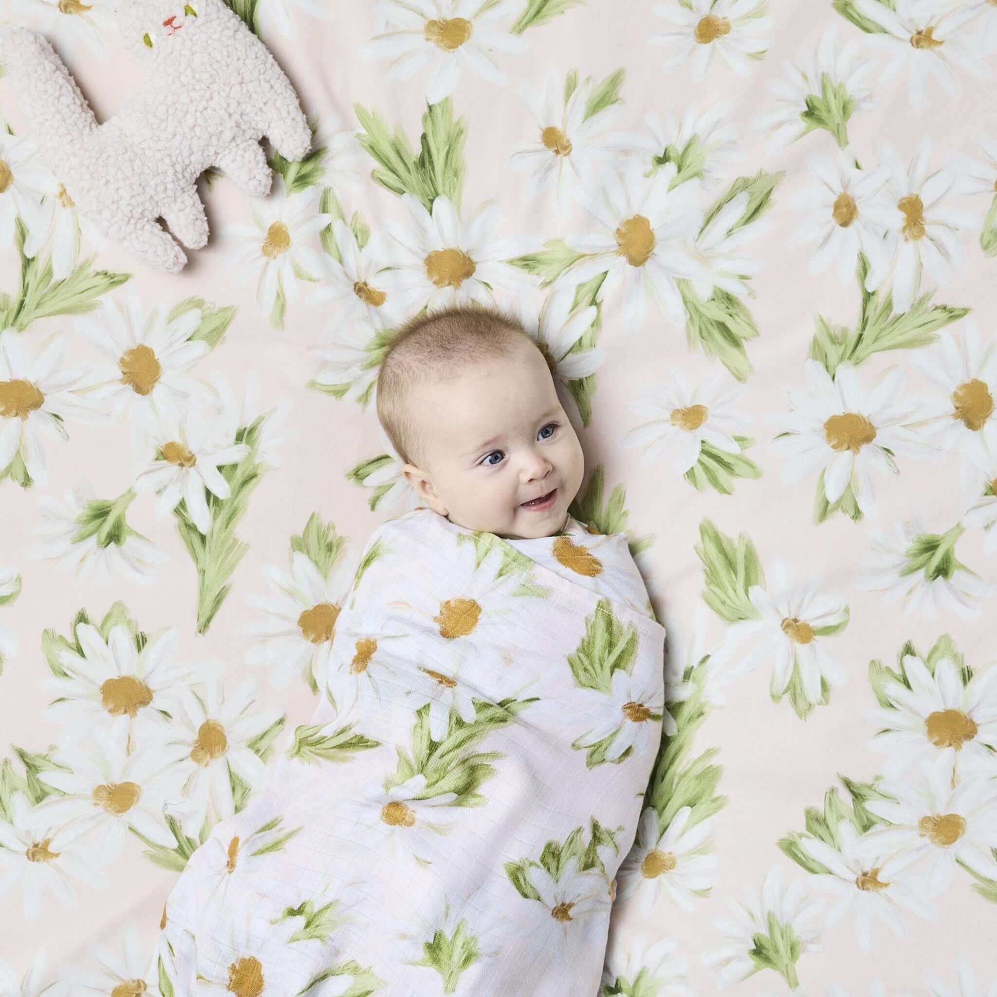 Alt Tag: Kip & Co Organic Cotton Baby Fitted Cot Sheet - Sweet Daisy pastel daisy floral nursery sheet with baby swaddled on top