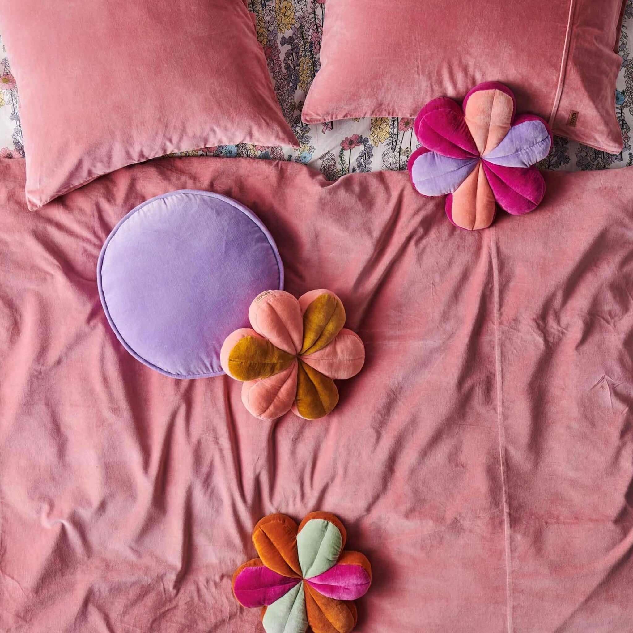 Alt Tag: Kip & Co Velvet Pea Cushion - Lilac round lilac cotton velvet cushion on pink bed with flower cushions