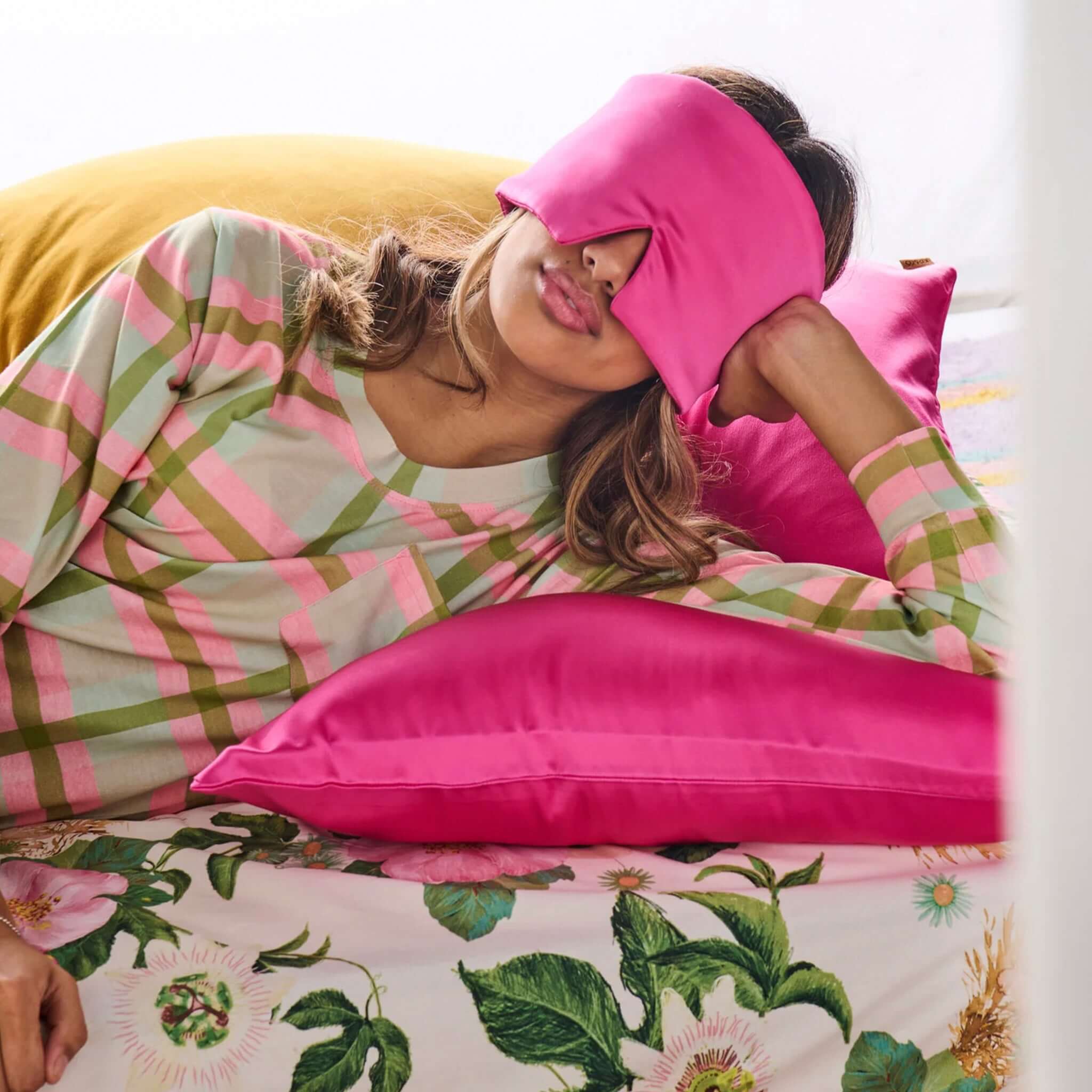 Alt Tag: Kip & Co Block Out Silk Eye Mask - Perfect Pink worn by woman resting on bed, 100% mulberry silk blackout sleep mask