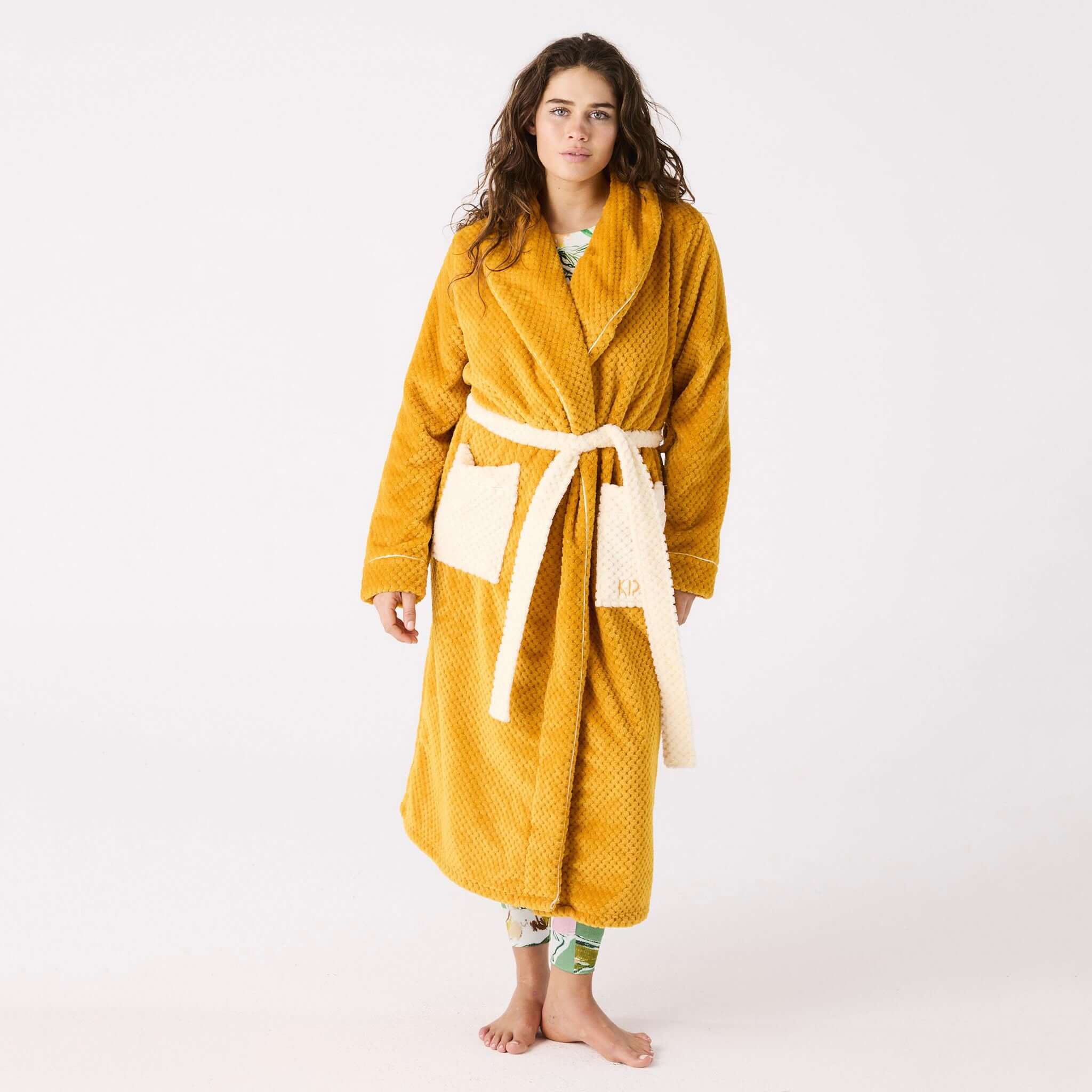 Alt Tag: Kip & Co Cosy Robe - Desert Sand quilted mustard robe with cream patch pockets and waist tie, model wearing full length