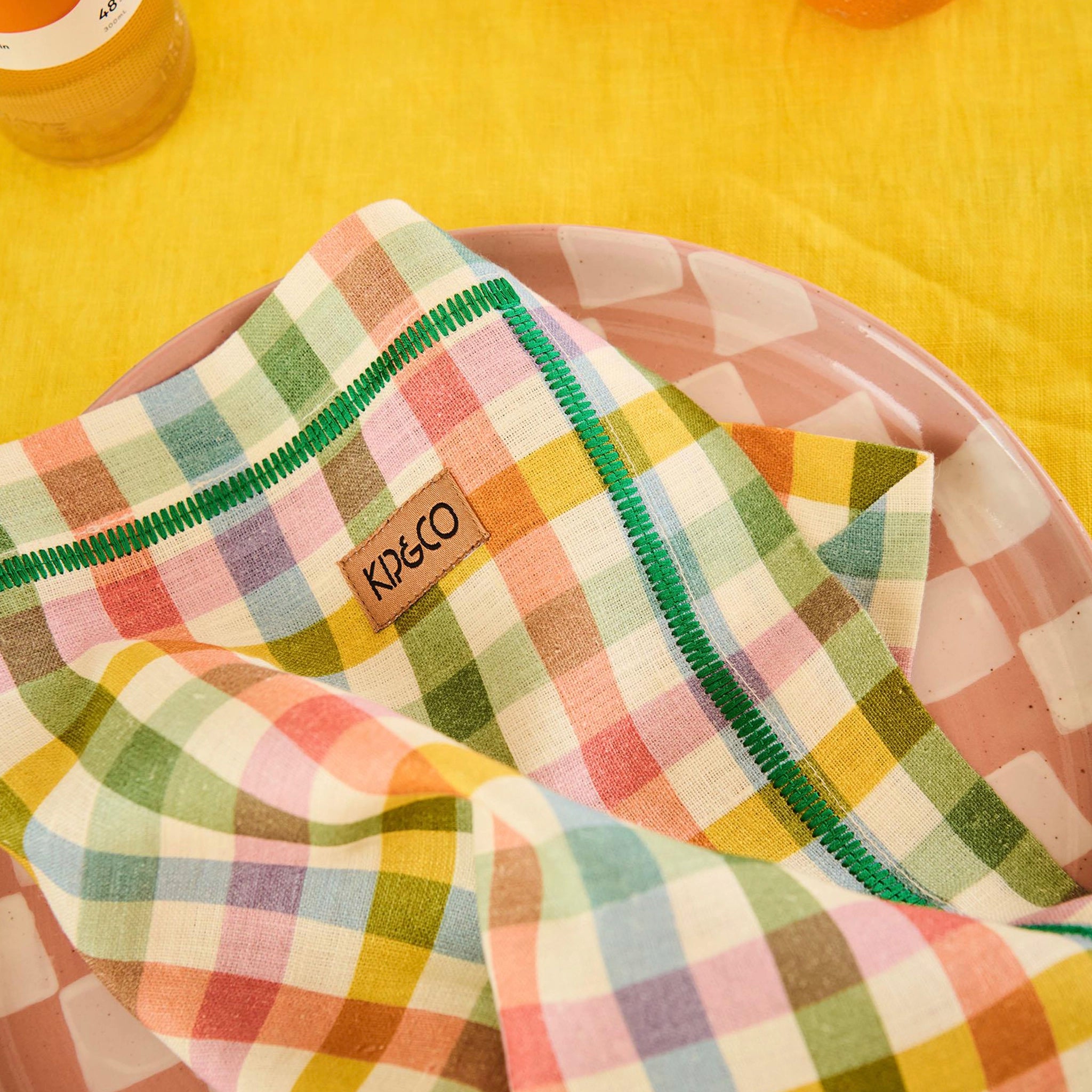 Colorful checkered napkin with 'Kip & Co' brand label on a yellow background