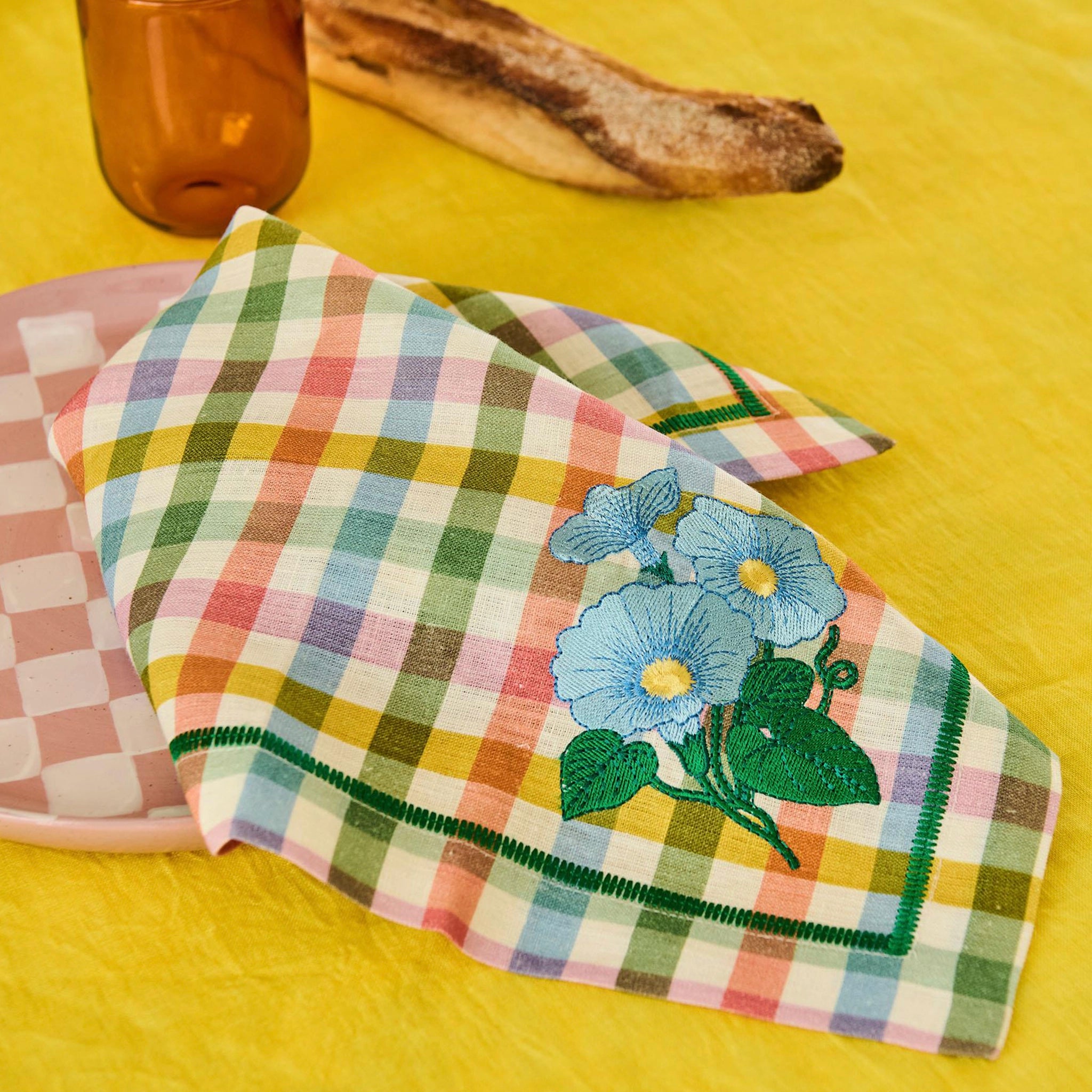 Checkered napkin with floral embroidery on a yellow background