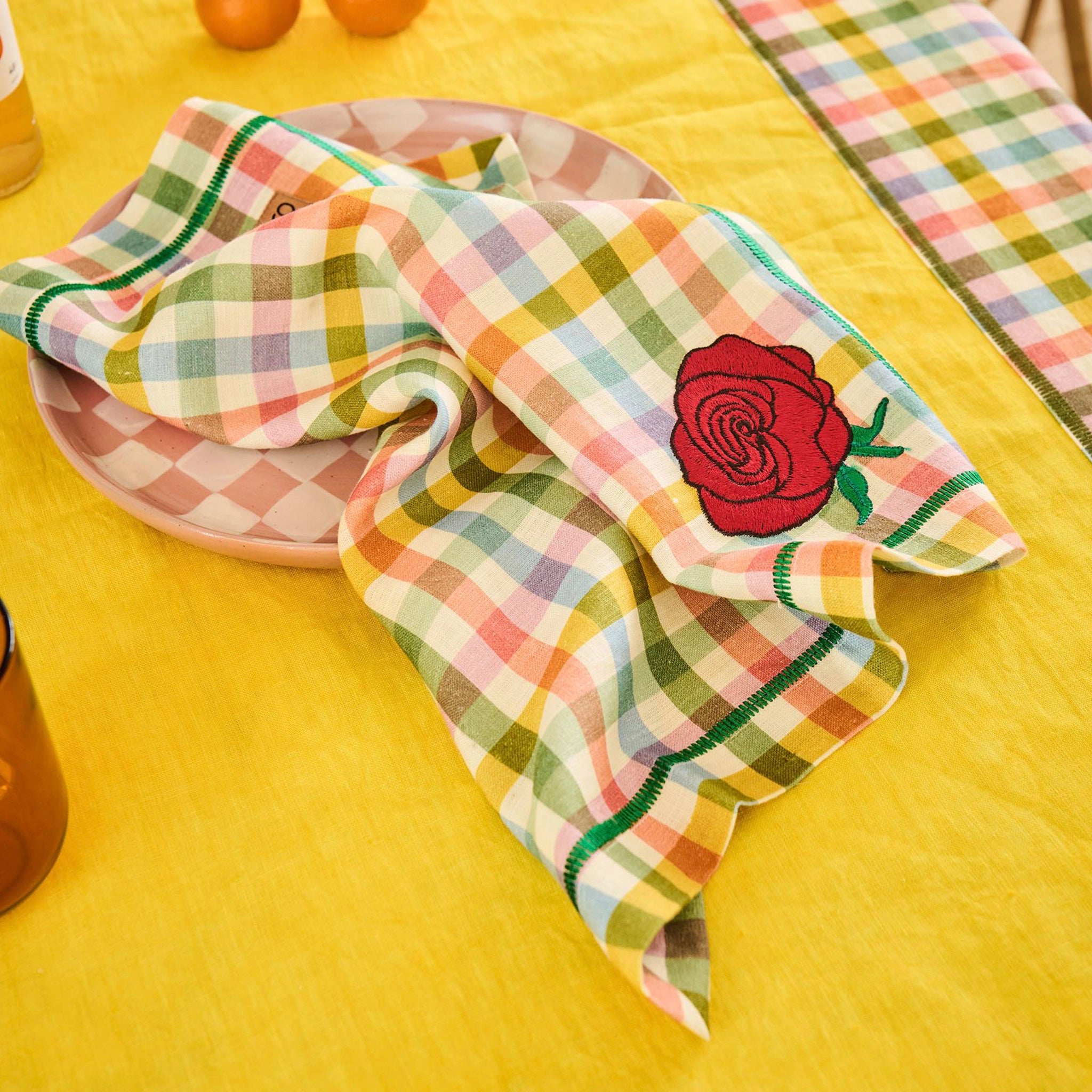 Checkered napkin with a rose embroidery on a yellow tablecloth