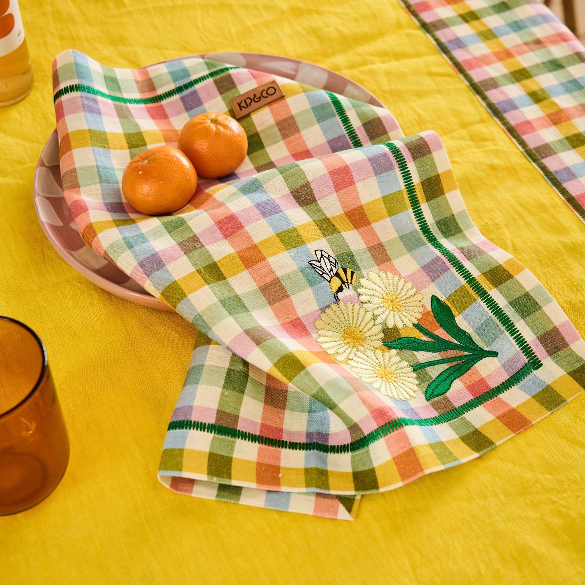 Checkered napkin with floral embroidery on a yellow tablecloth