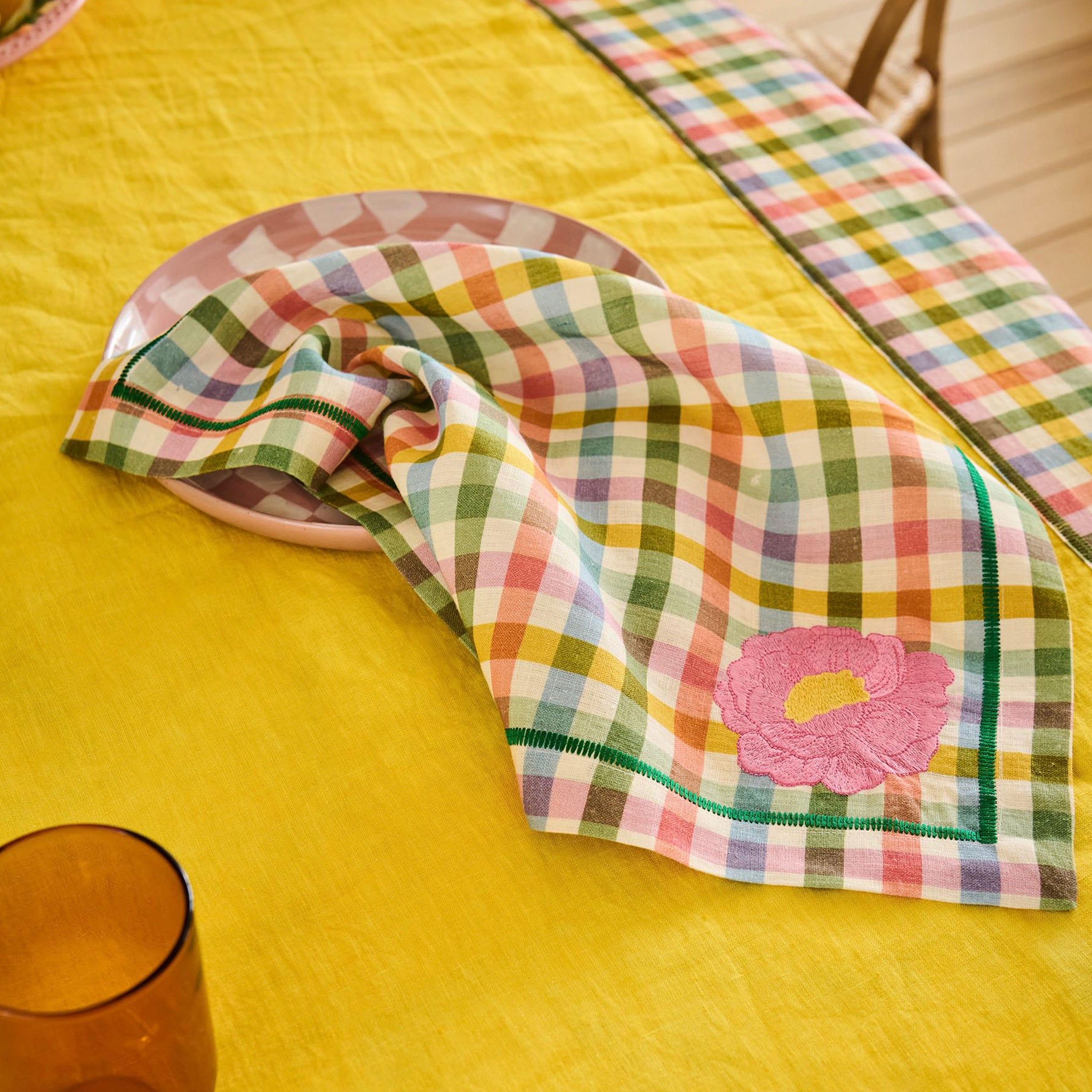 Colorful checkered napkin with a pink flower on a yellow table
