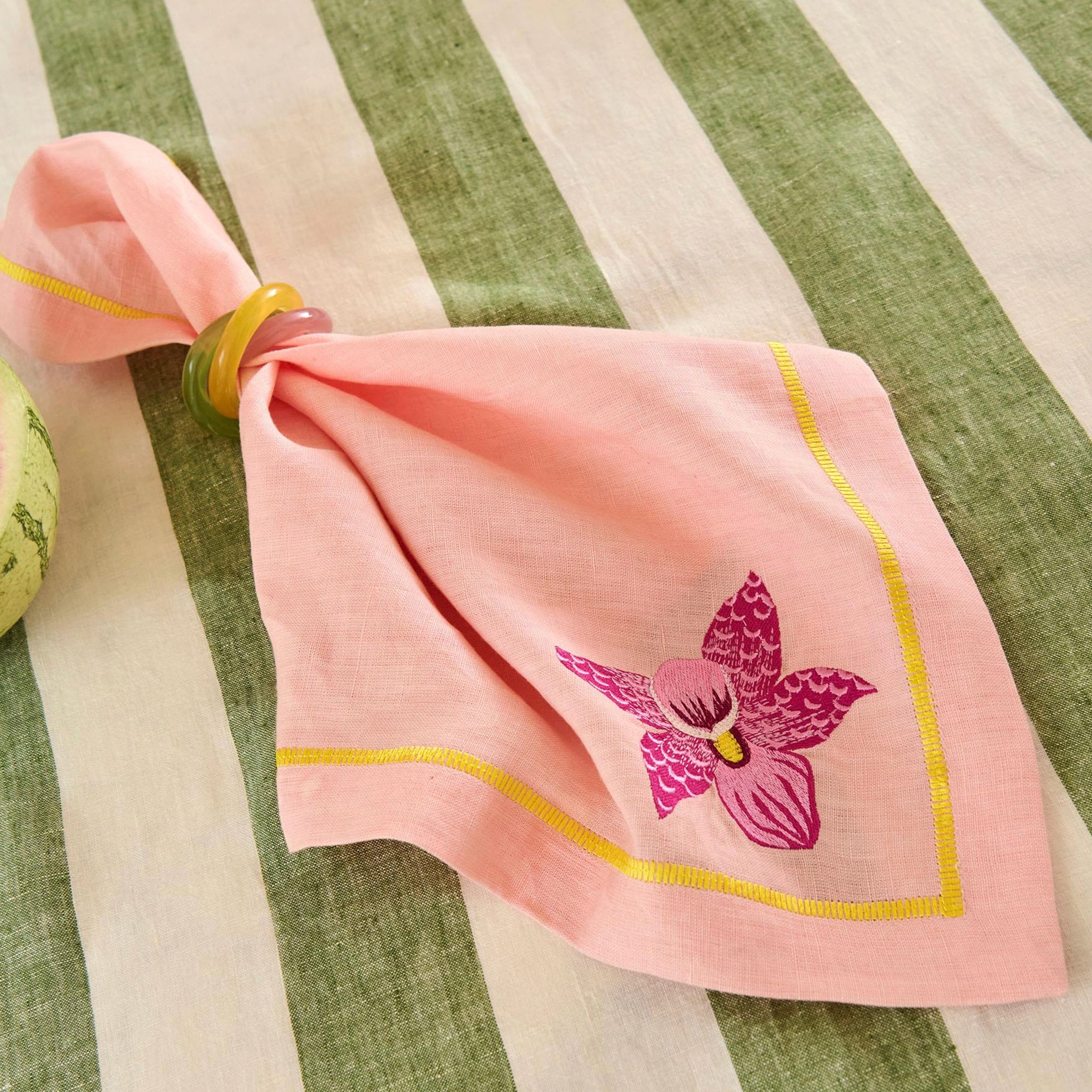 Pink napkin with floral design on a striped tablecloth