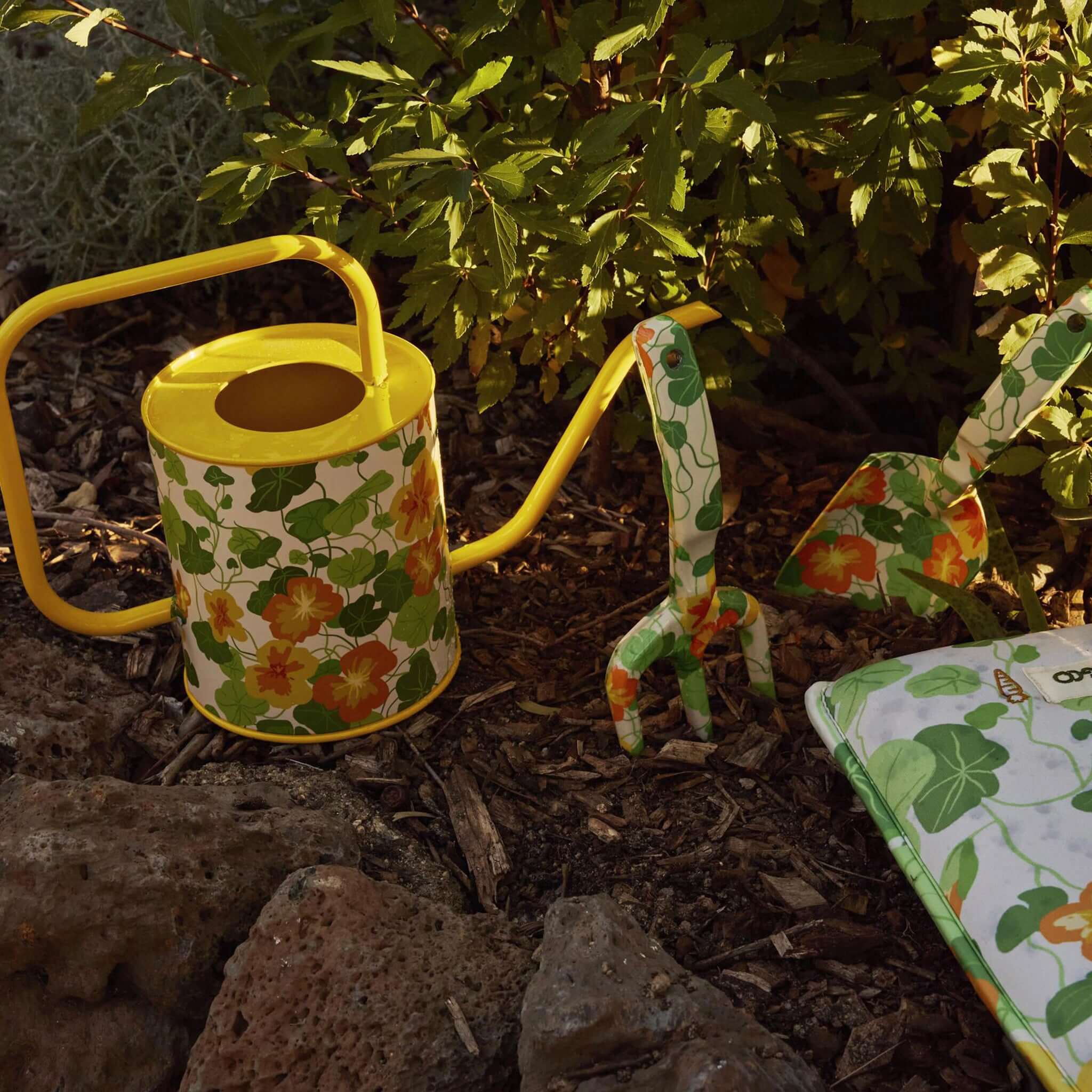 Alt Tag: Kip & Co Garden Tools & Gloves Set - Nasturtium watering can, hand fork and trowel with floral nasturtium print in garden